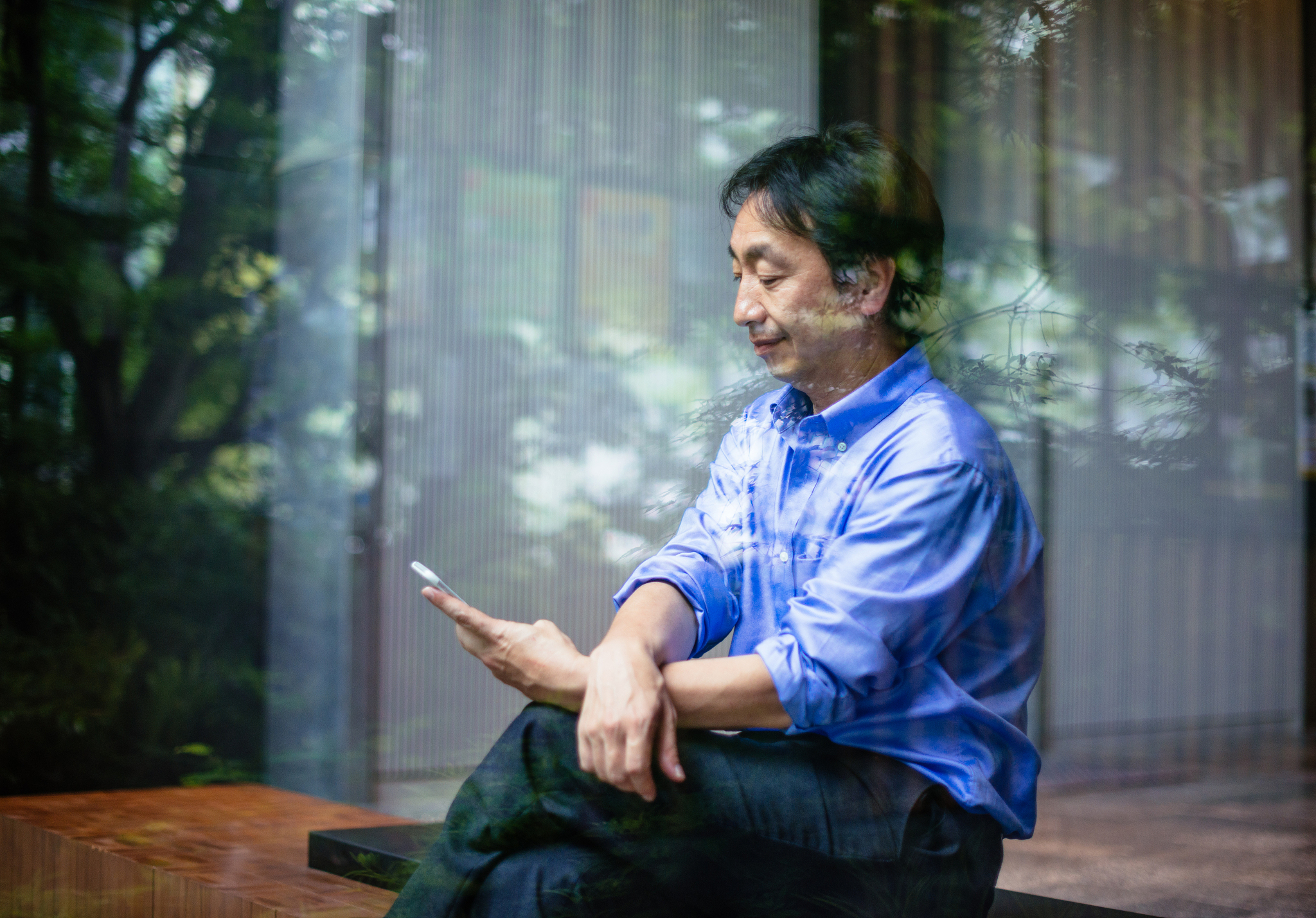 mature japanese businessman standing near glass in office