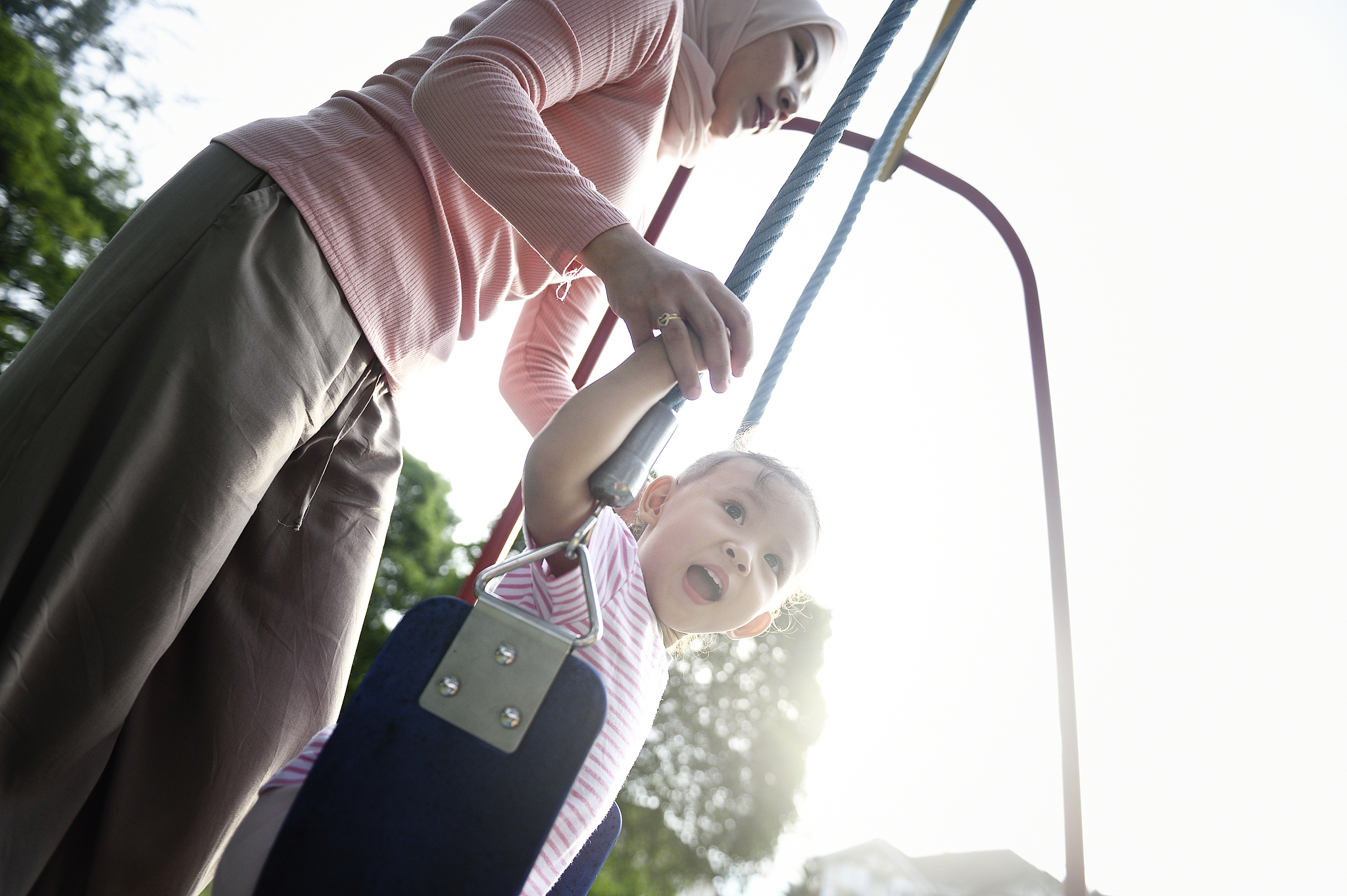 malay woman playing with her daughter on a swing at dawn