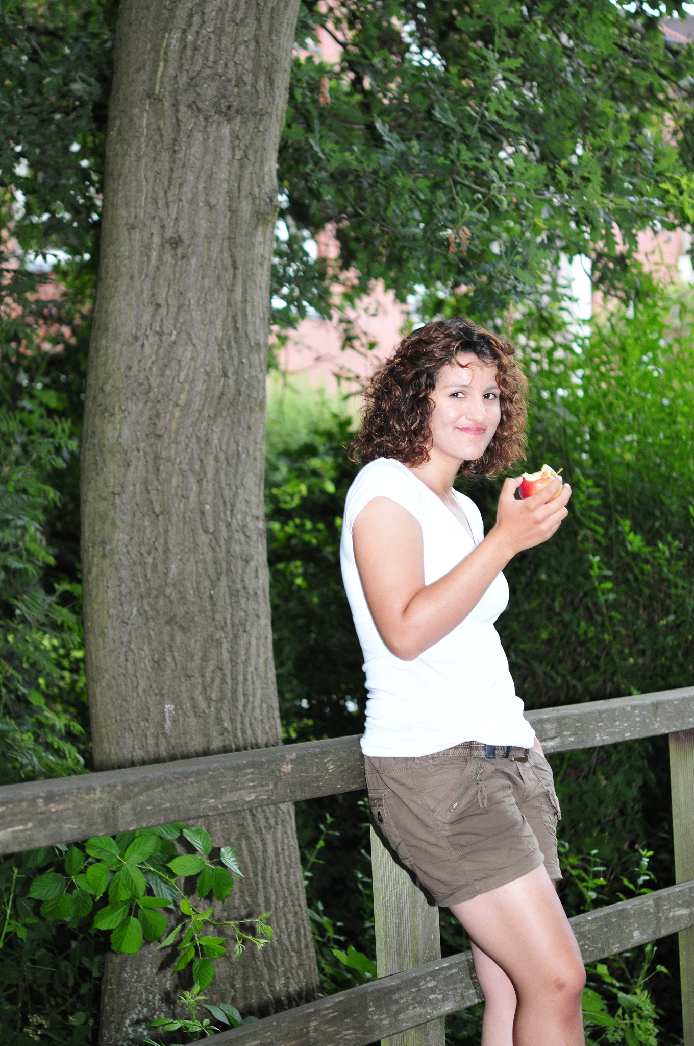 young woman stands in nature with an apple
