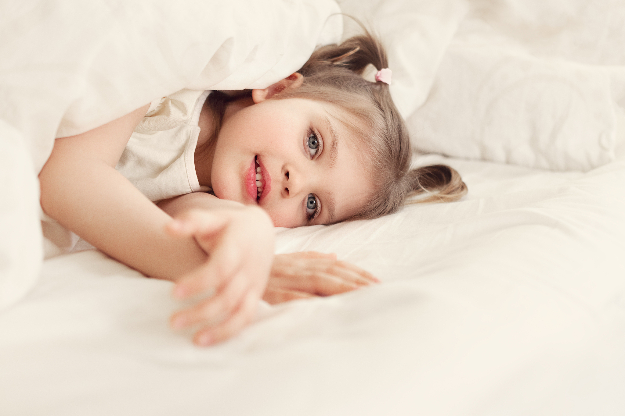 little cheerful girl 4 years old smiles and lies on bed on under