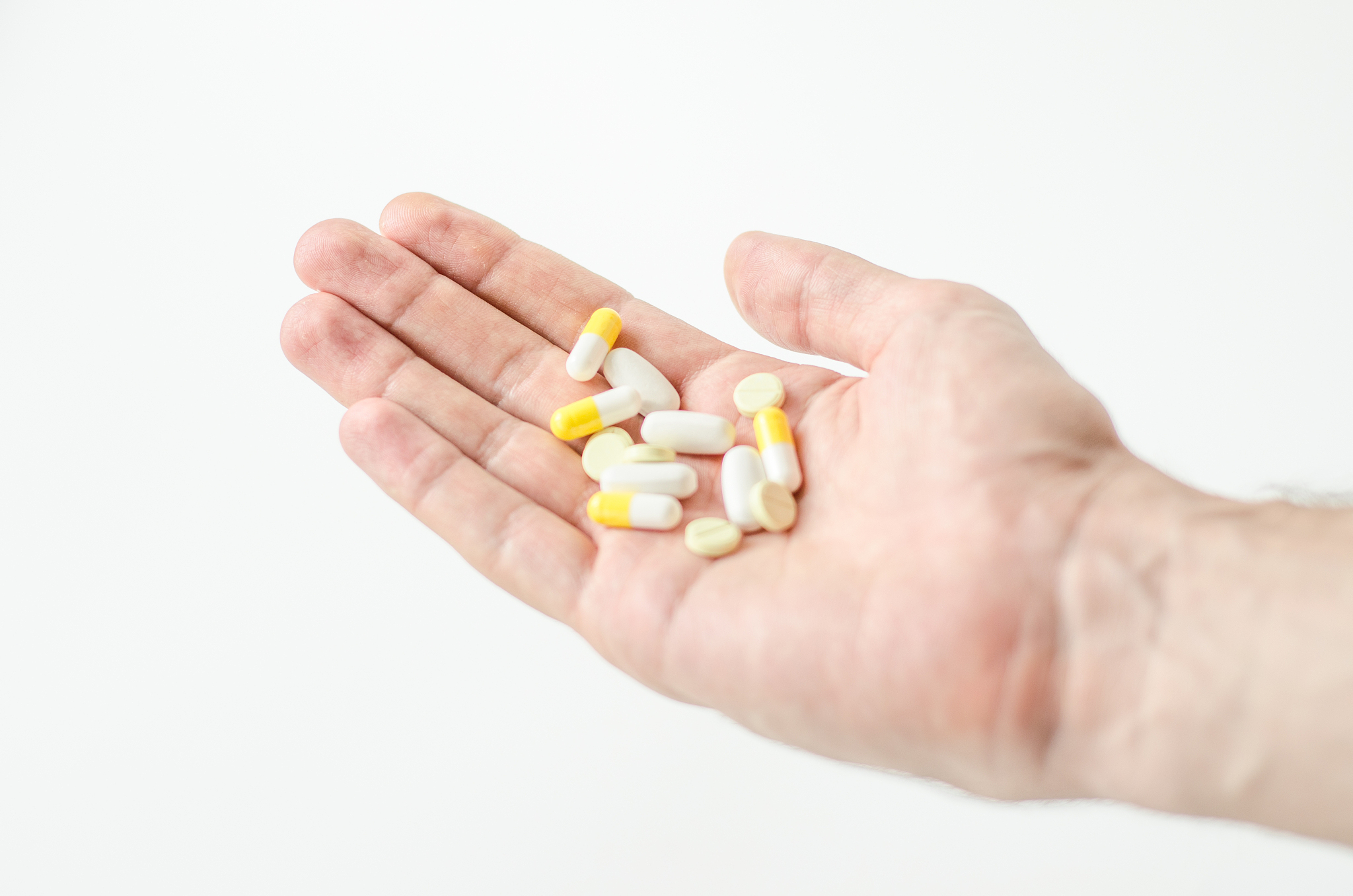 close up photo of one round pill in young male hand. man takes m