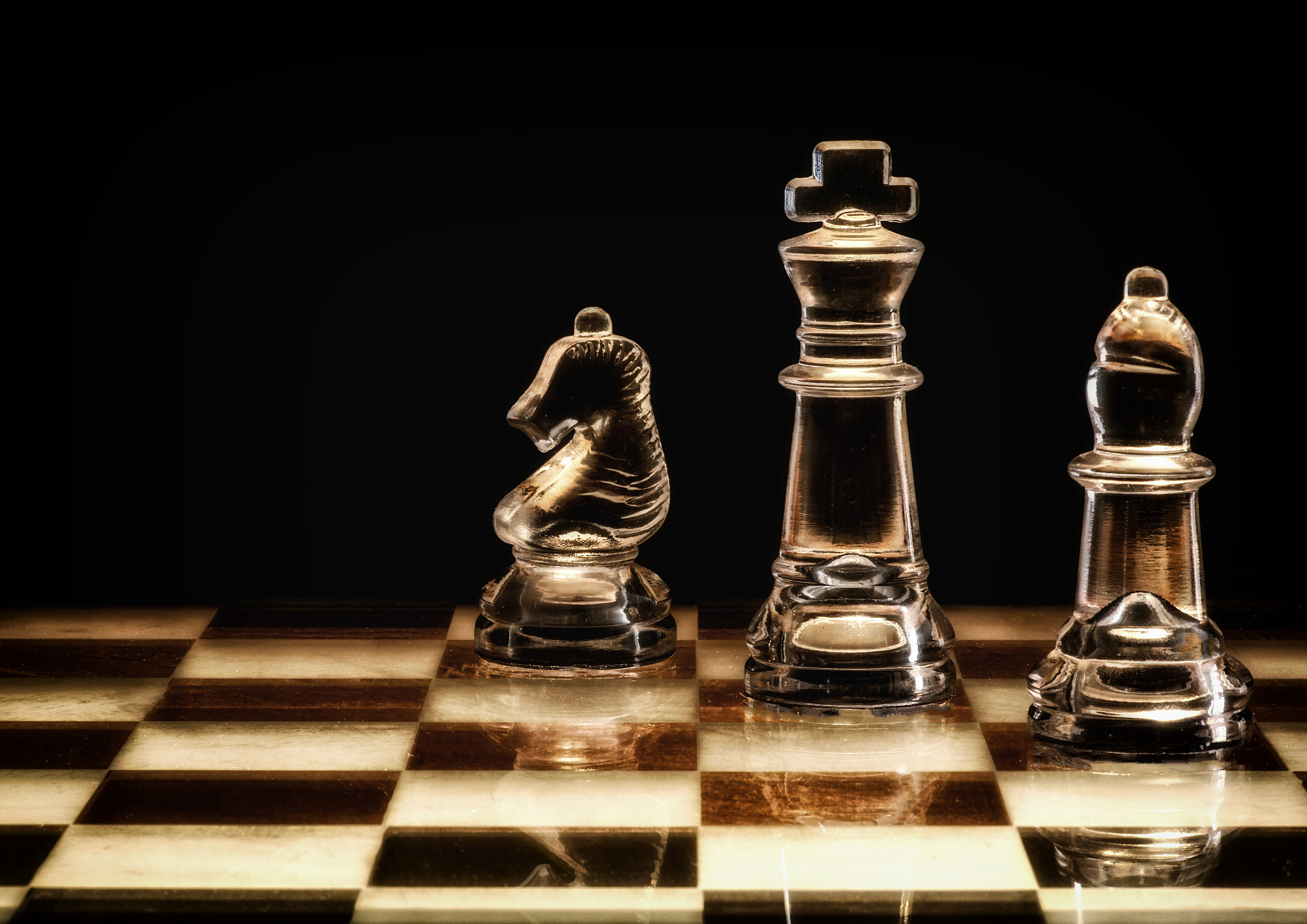 three glass chess pieces on a glass chess board