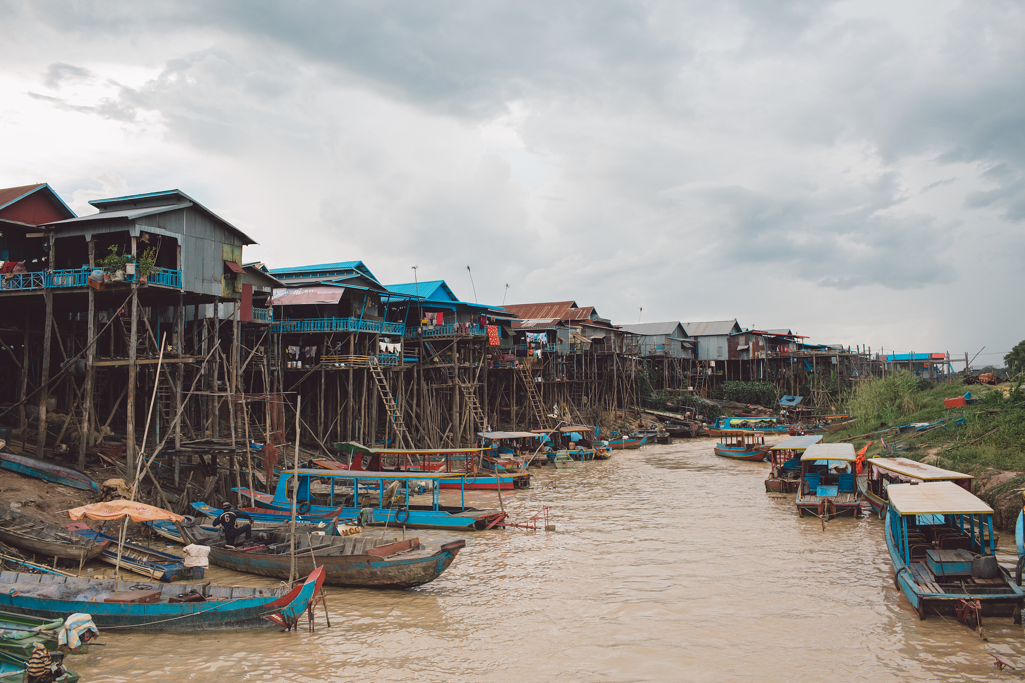 boats moored on beach by houses against sky