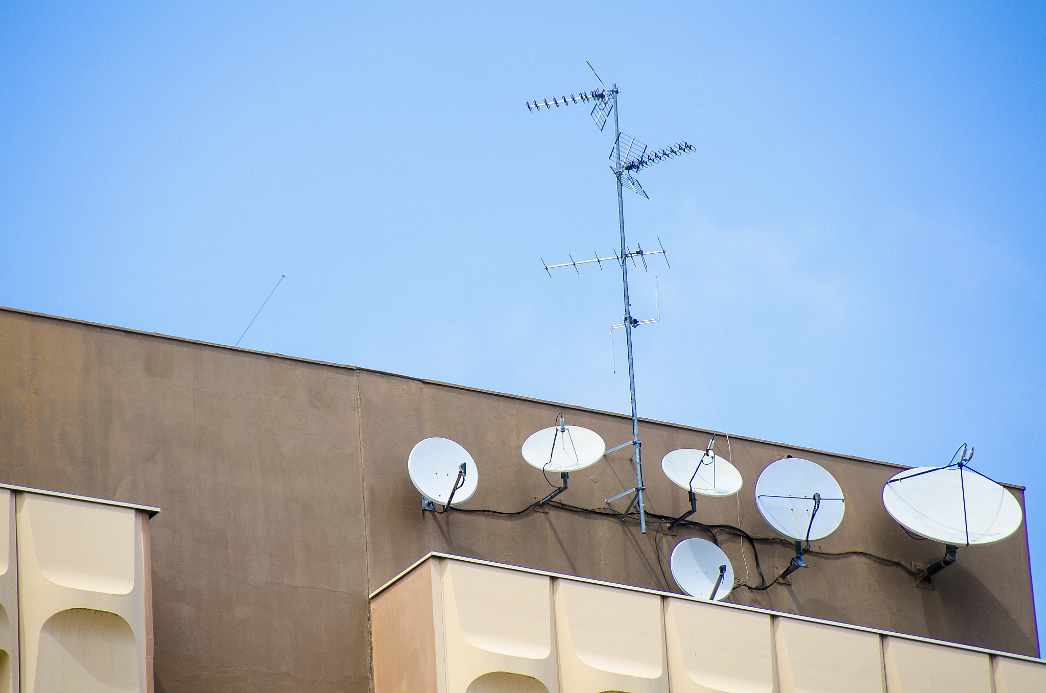 low angle view of antennas and satellite dishes on building agai