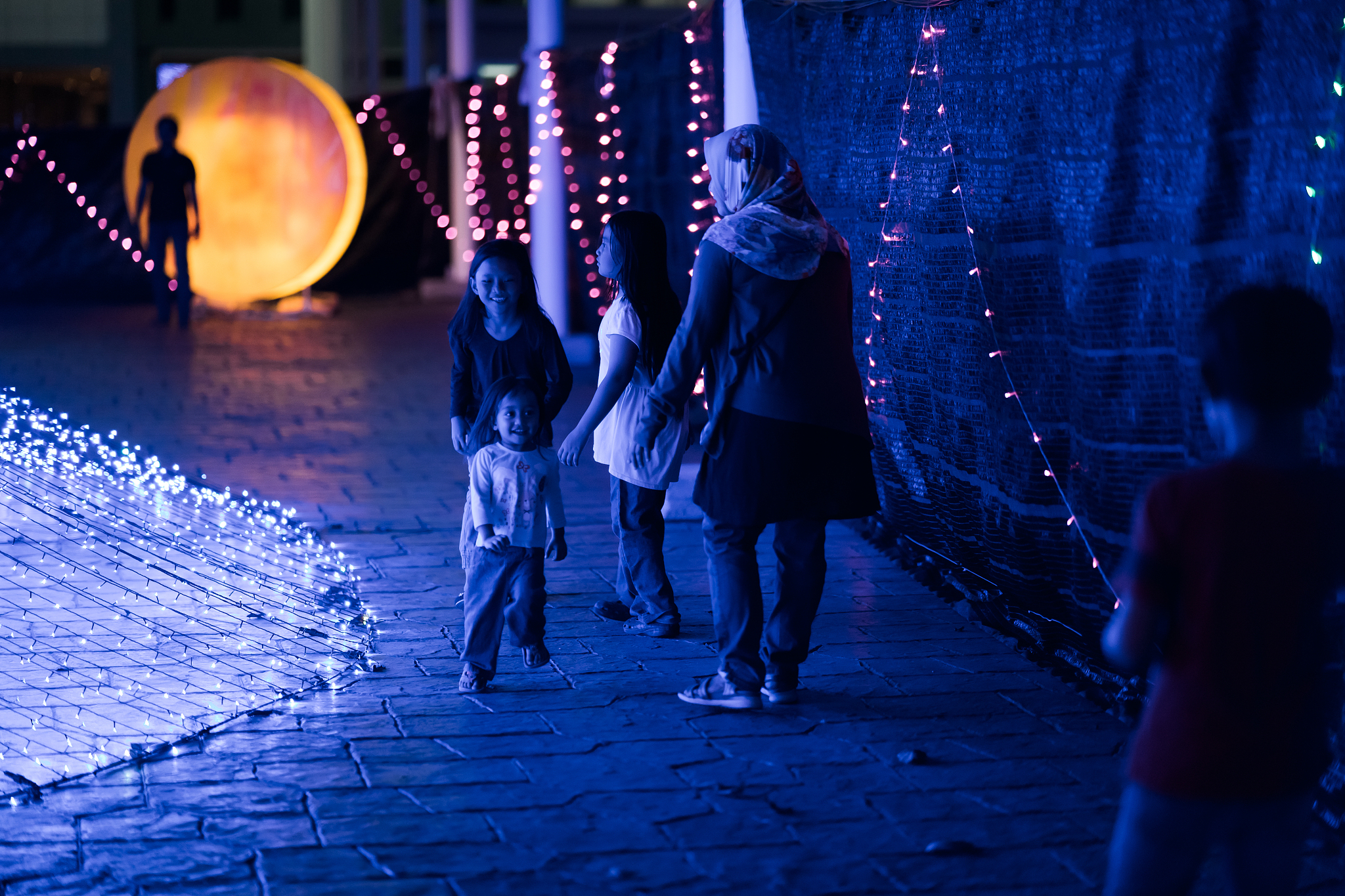 people walking on illuminated footpath at night