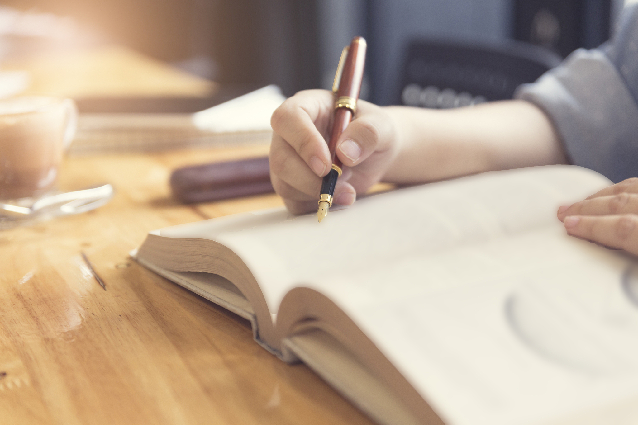 woman's hand reading book with pen, tablet and notebook