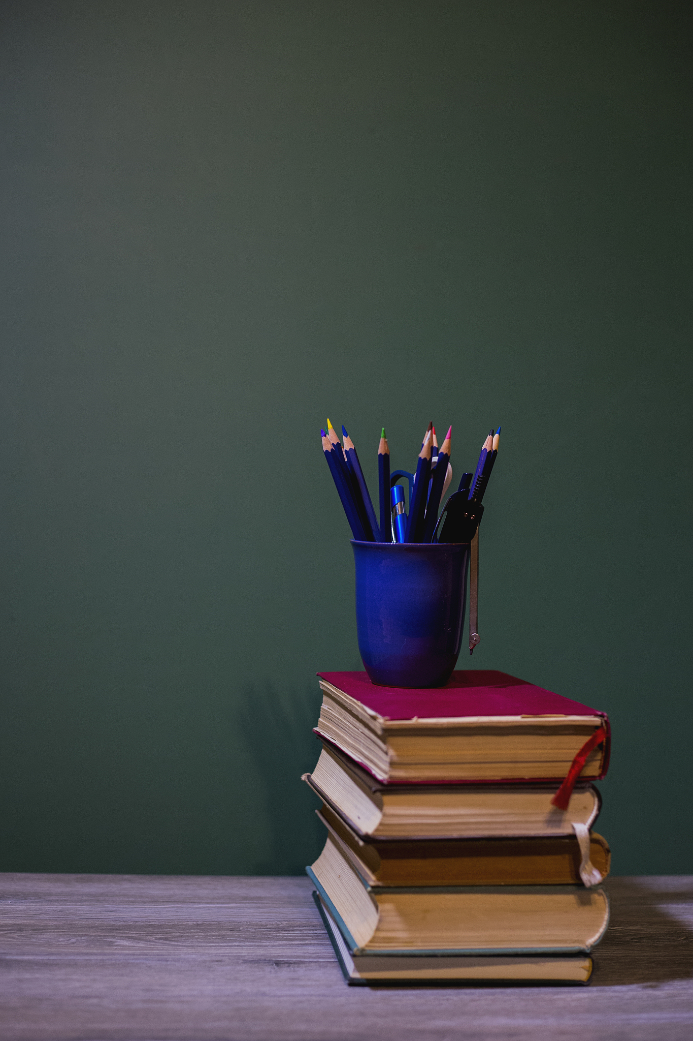 books and pencils on a wooden shelf. on a wooden background.