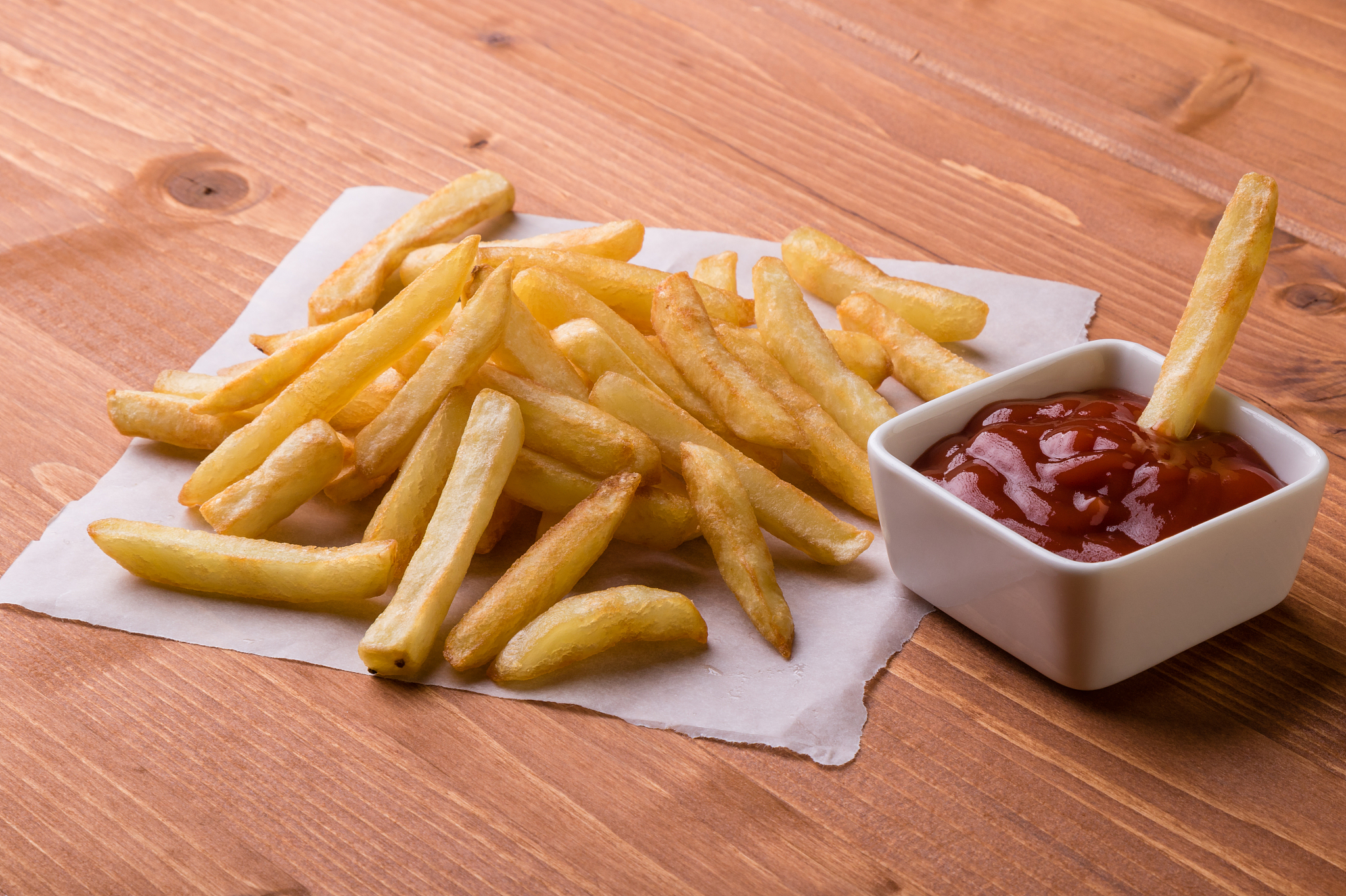 fries on a wooden table with ketchup