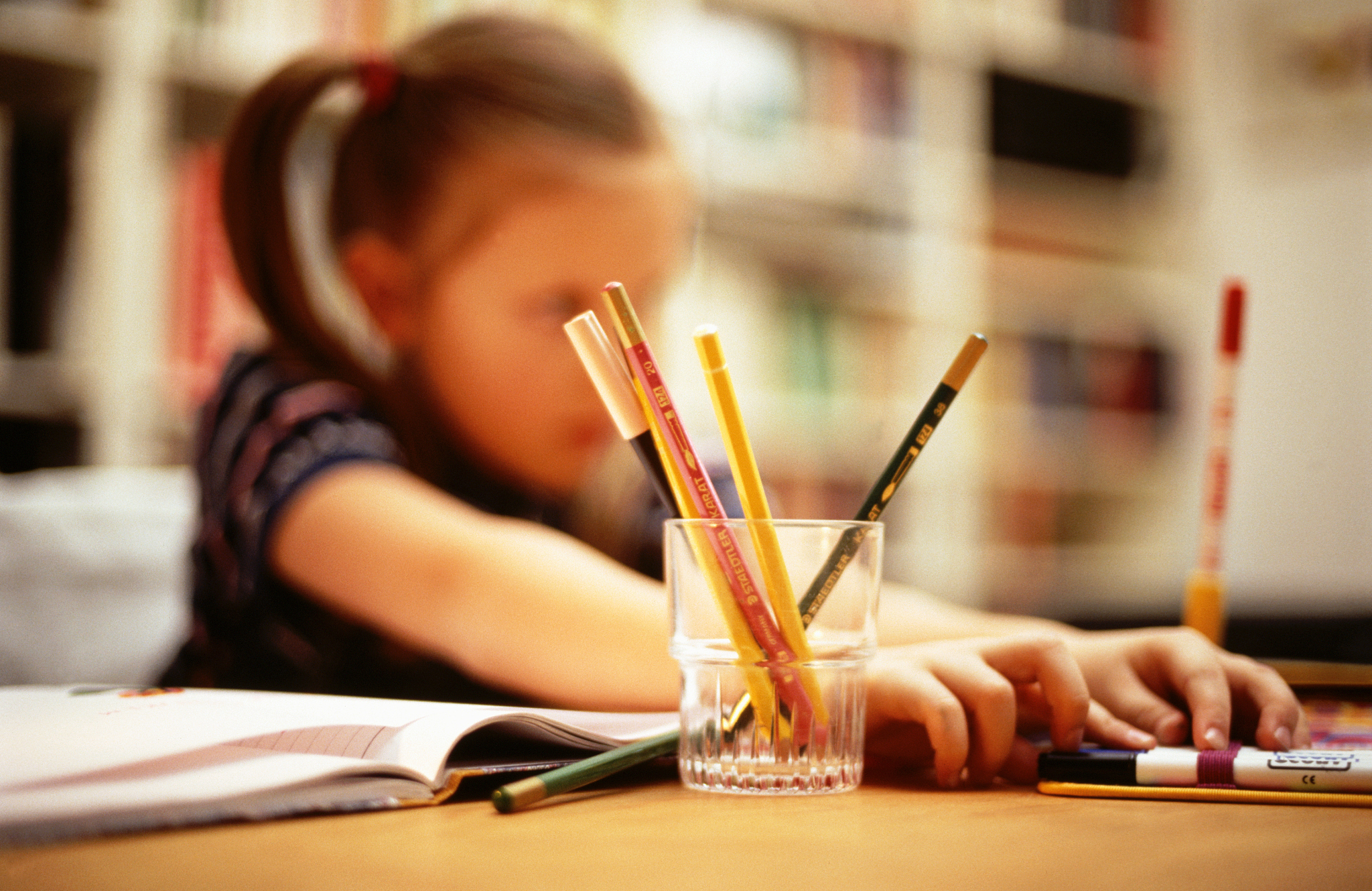 girl sitting at the table with many pens