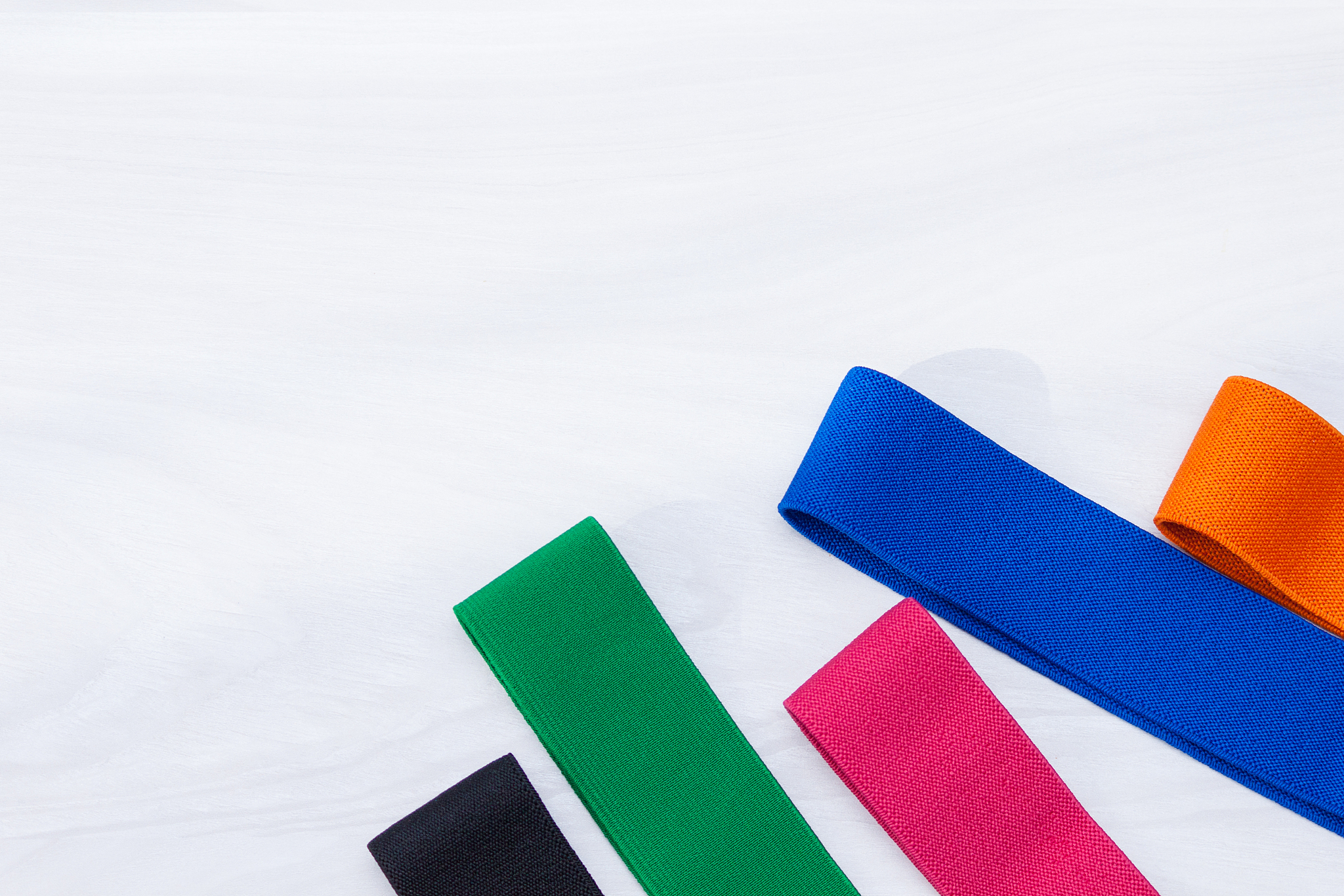 a set of multi-colored elastic rubber bands for fitness on white