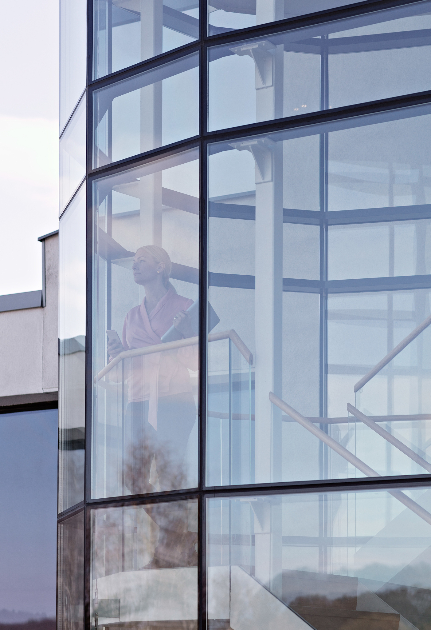 thoughtful businesswoman standing in office seen through glass