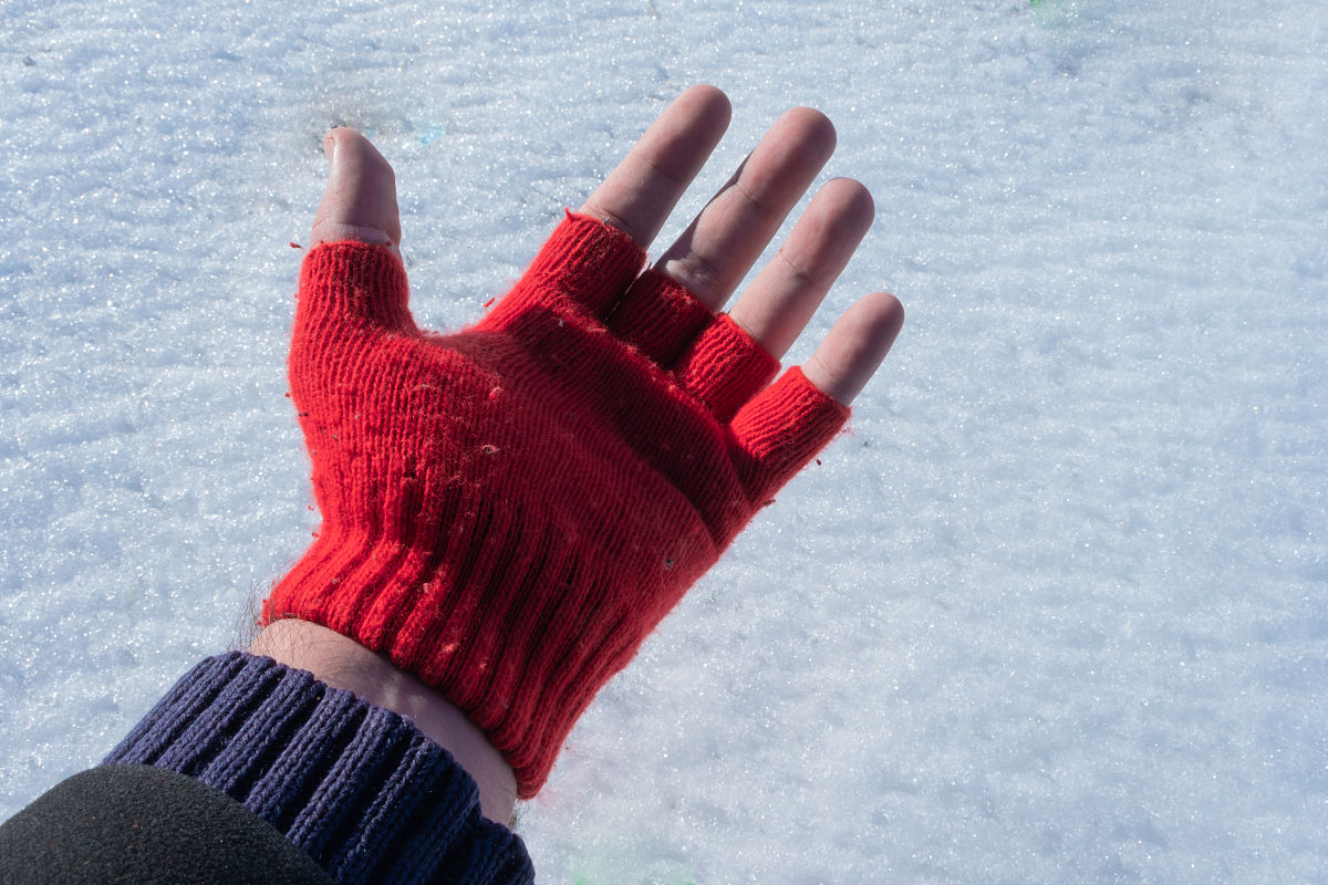 一个男人的左手在雪地上露出他的红色手套