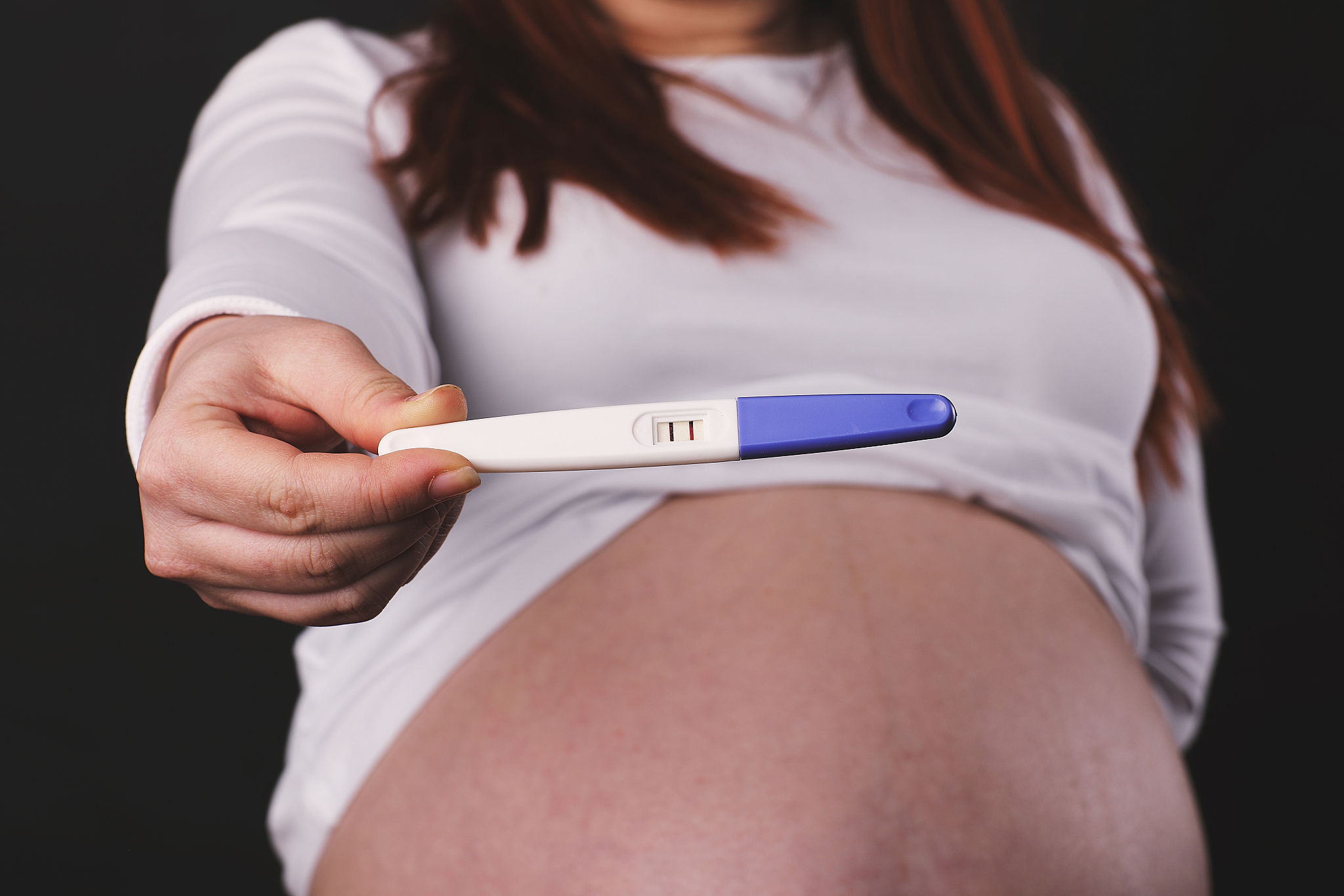 pregnant woman holding pregnancy test