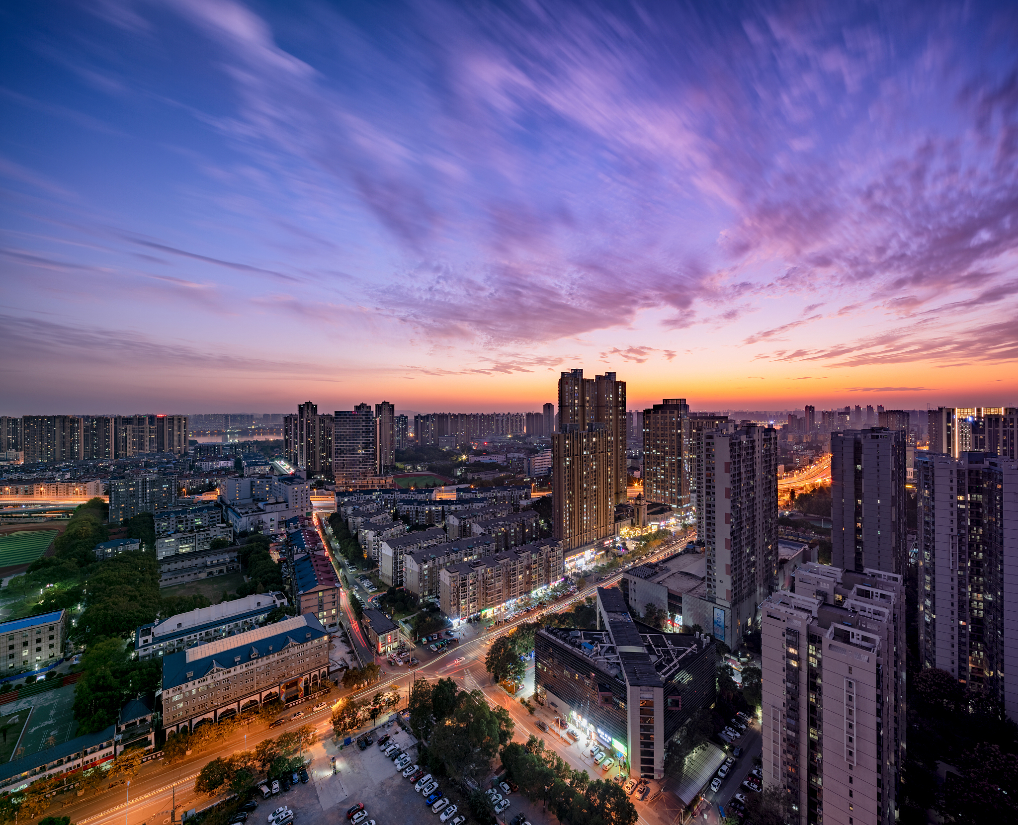 aerial view of illuminated buildings against sky during sunset