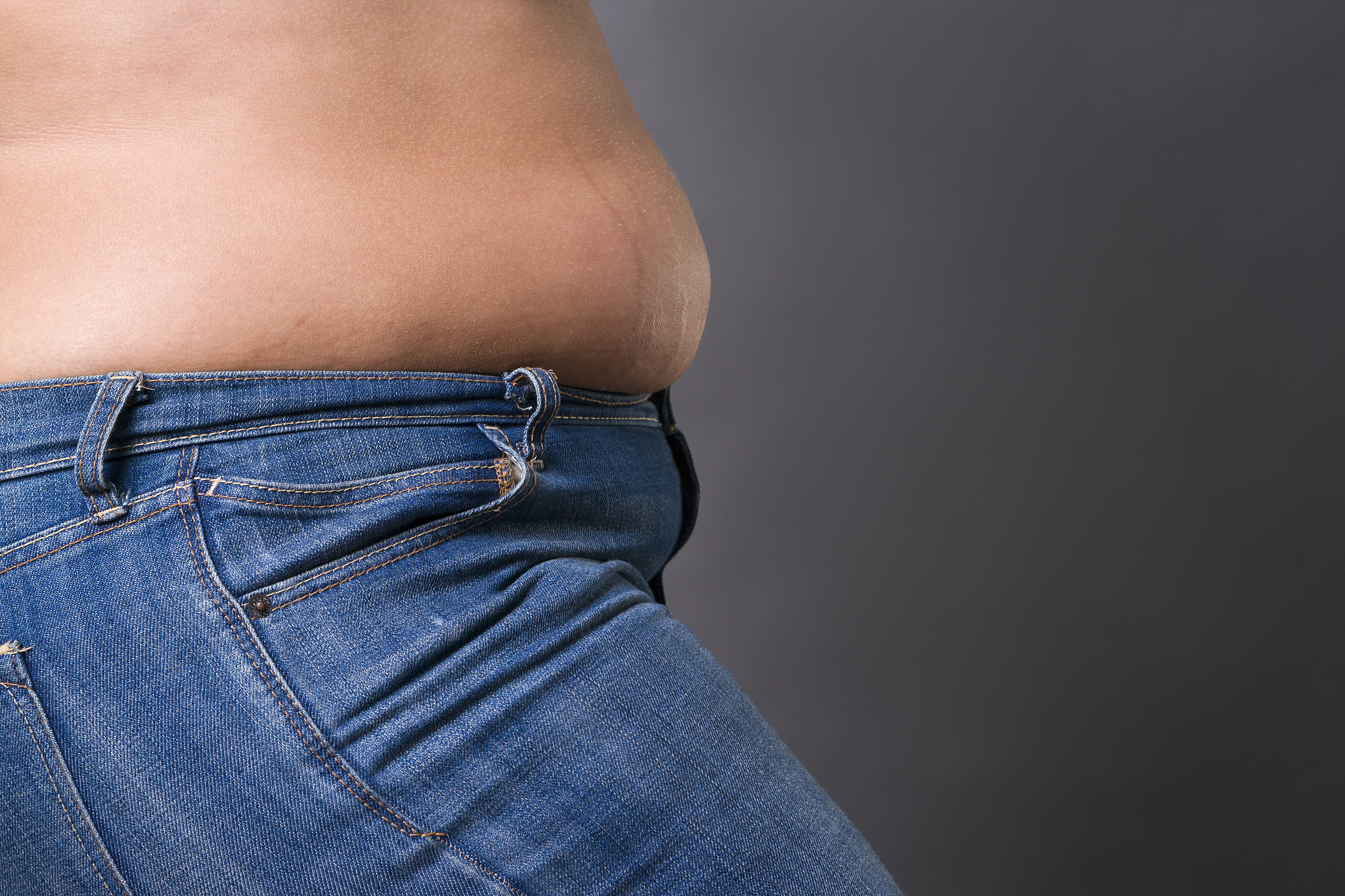 woman with fat abdomen in blue jeans, overweight female stomach,