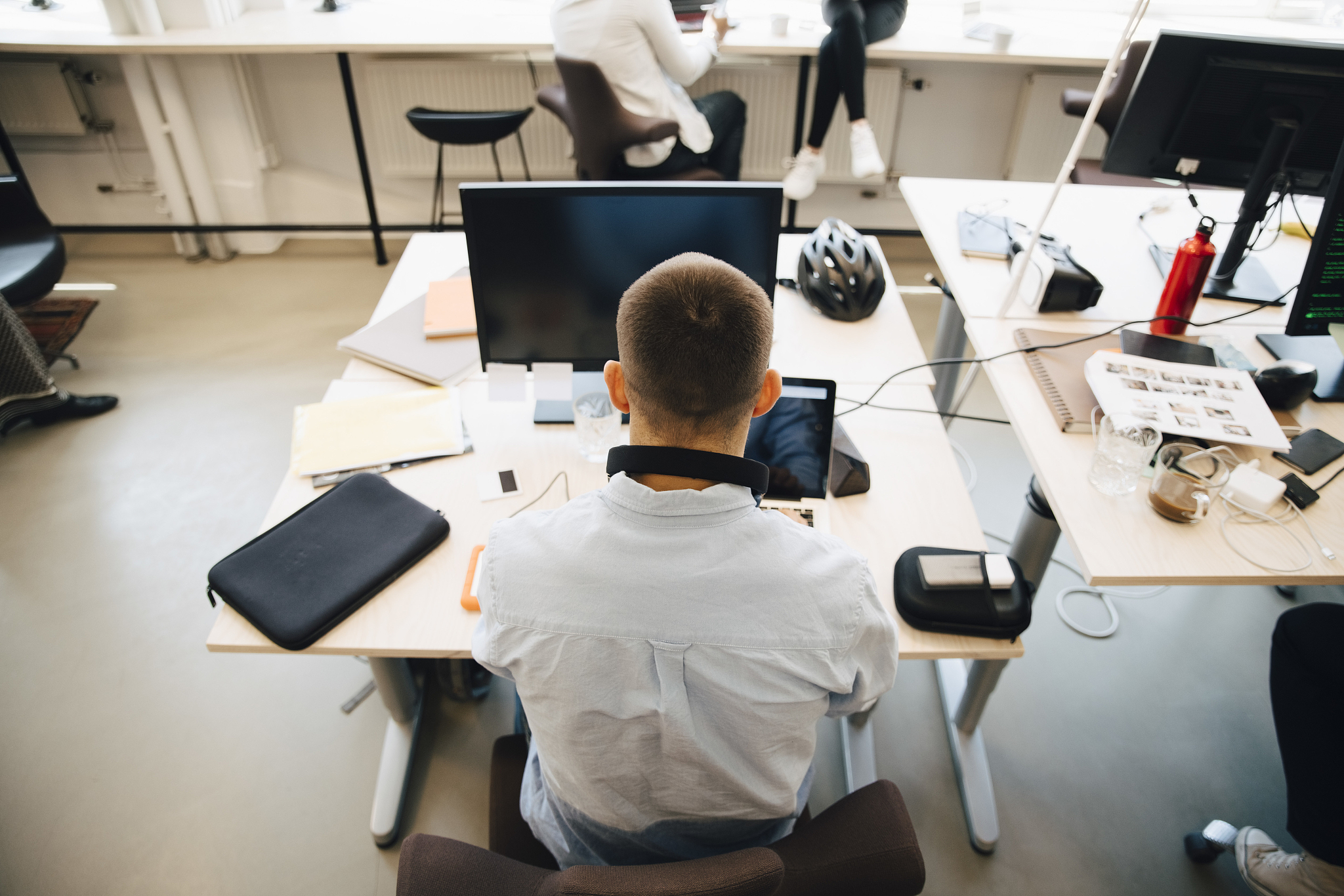 rear view of male computer programmer using laptop on desk while