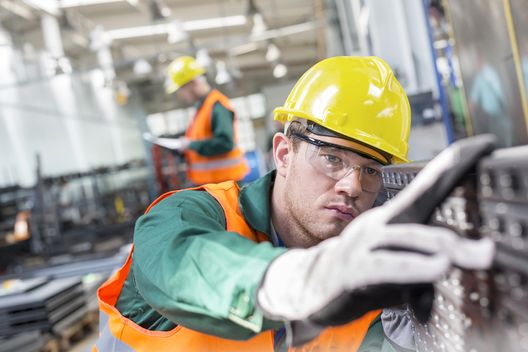 focused worker examining steel part in factory