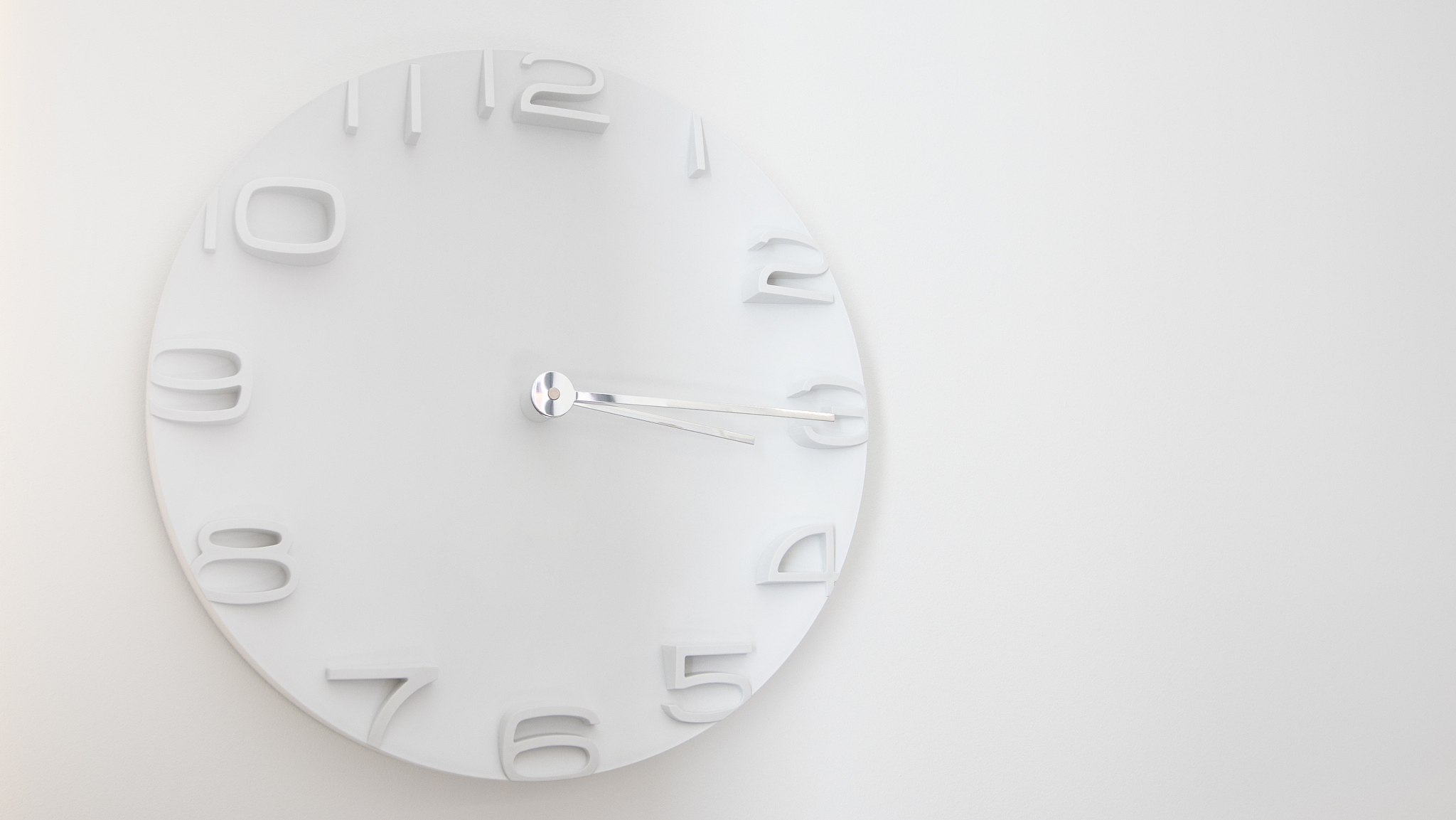 white wooden clock on white wall with warm light in late morning