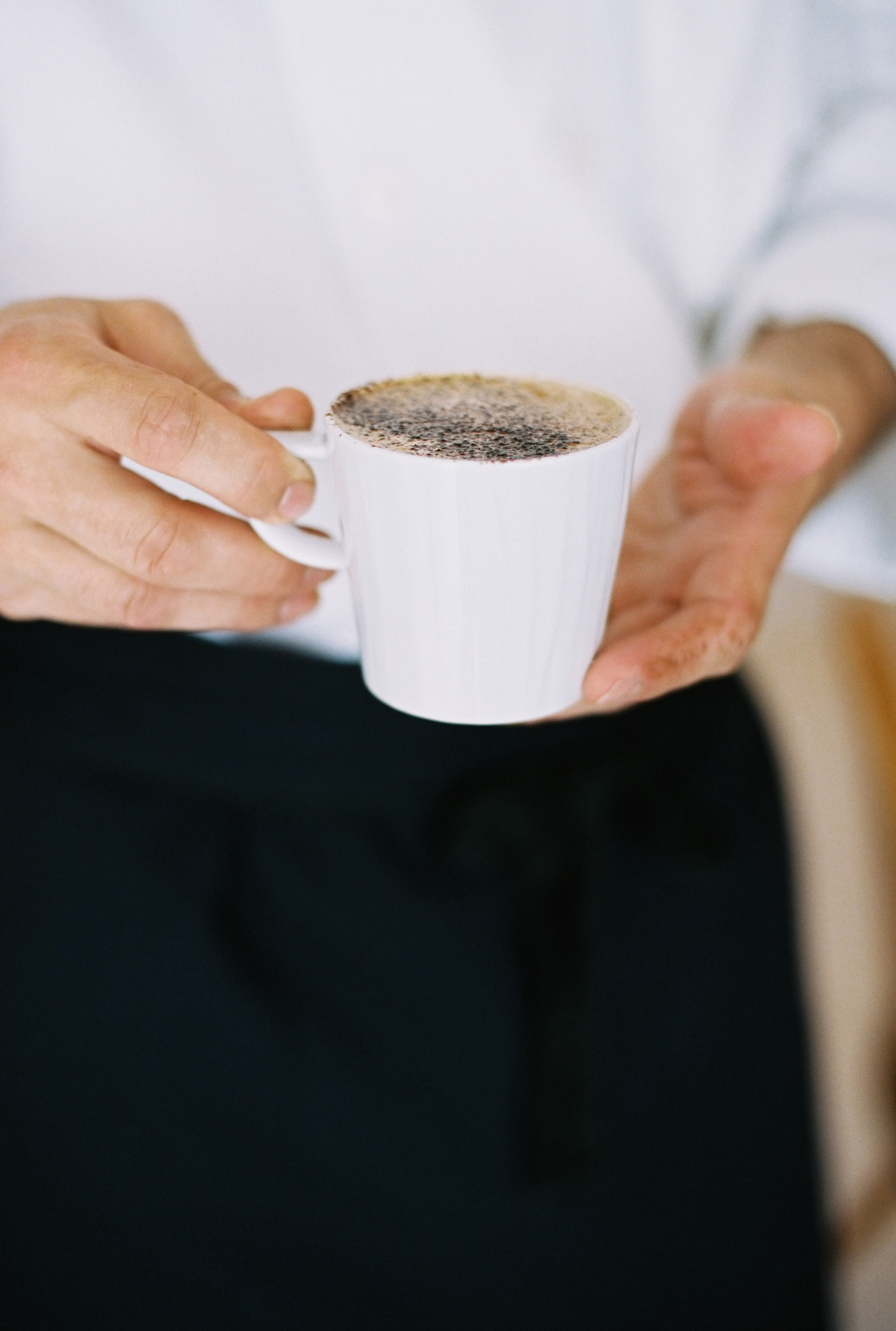 a person holding a full cup of coffee. froth.