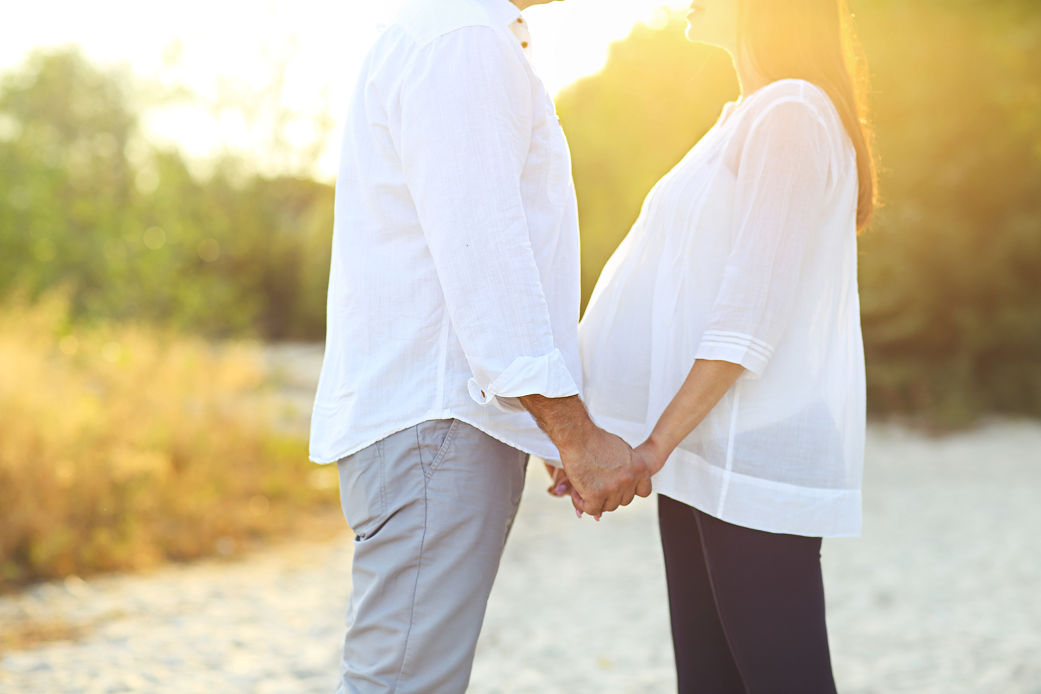 young happy pregnant family on the beach
