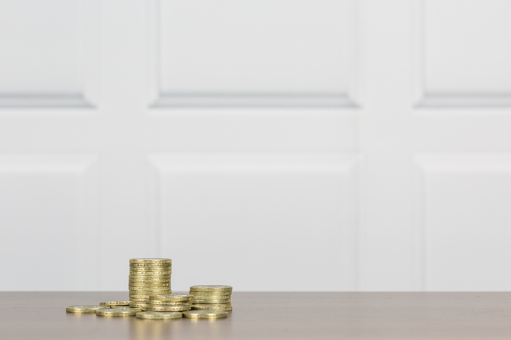 gold coins on a wooden table surface with white contemporary pan