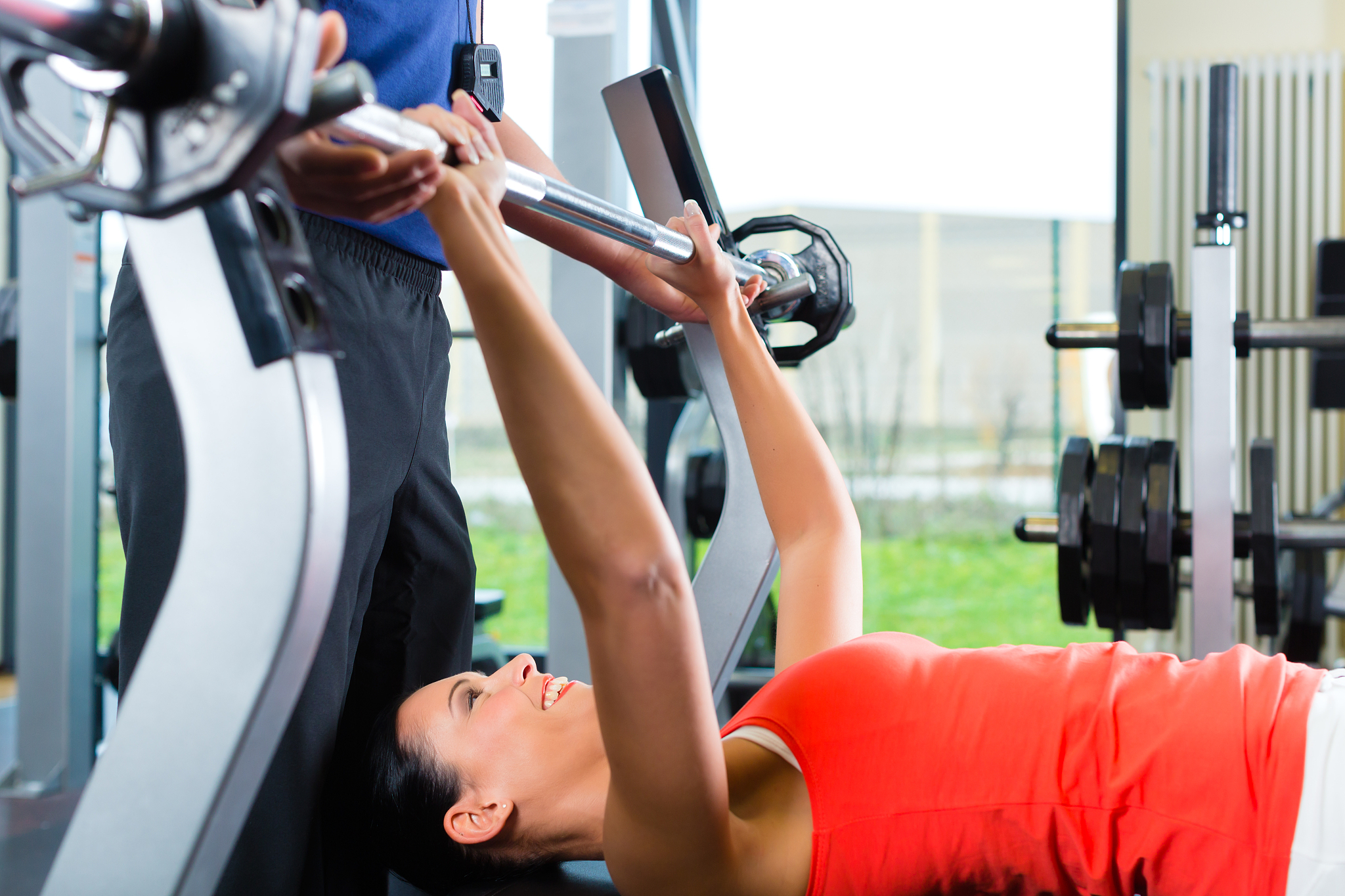 woman and personal trainer in gym, with dumbbells