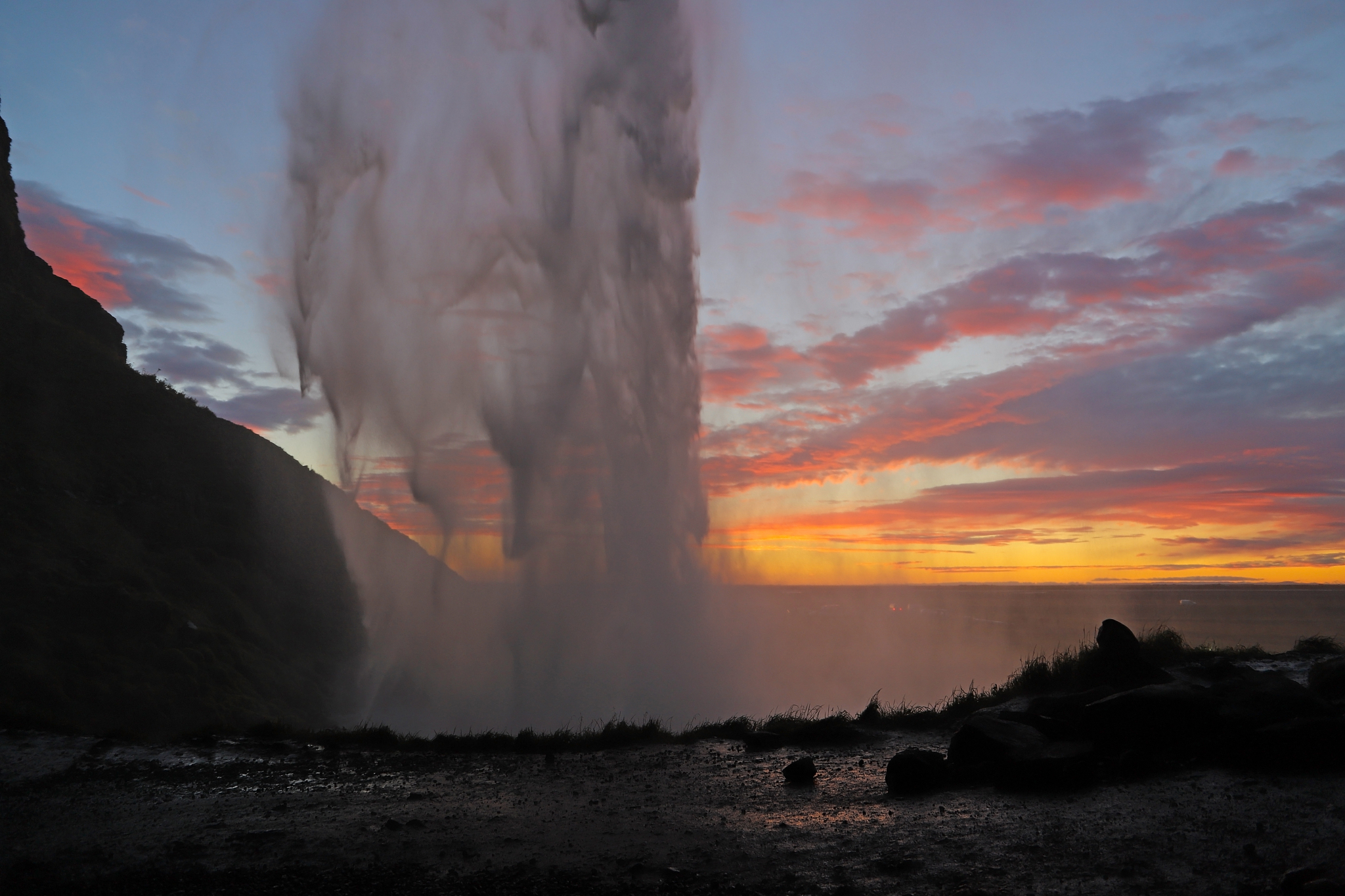 cascade of water falls from a tall cliff at sunset. a scenic vie