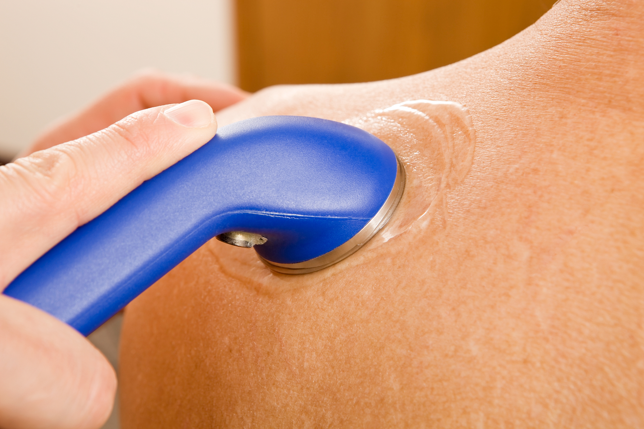 chiropractor performing an ultrasound on a patient's shoulder