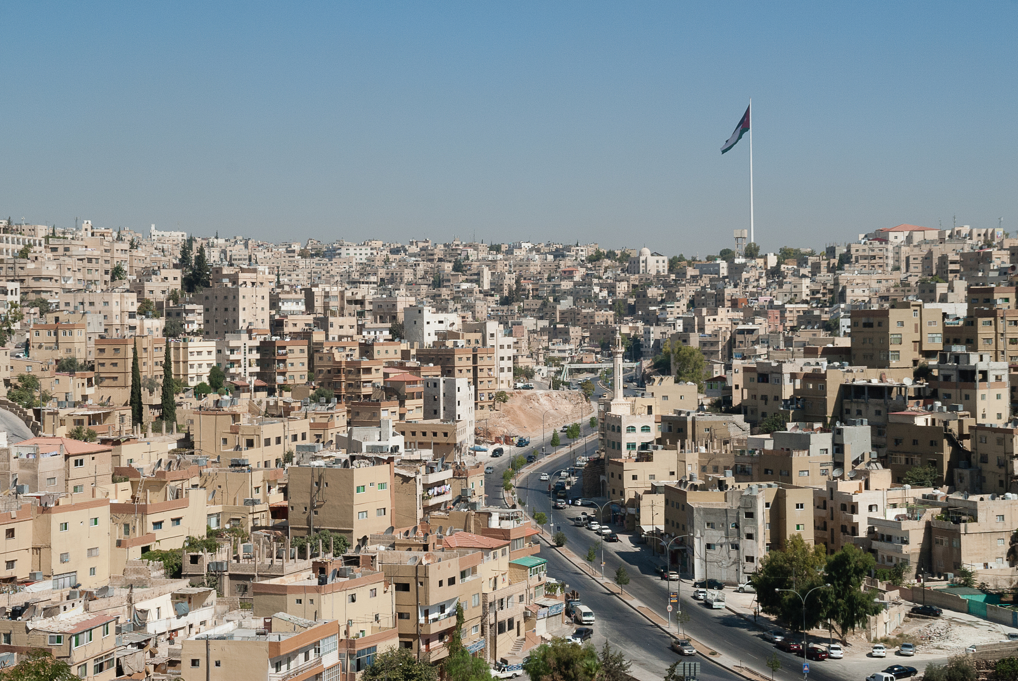 large flag pole and flag and buildings in amman skyline, jordan