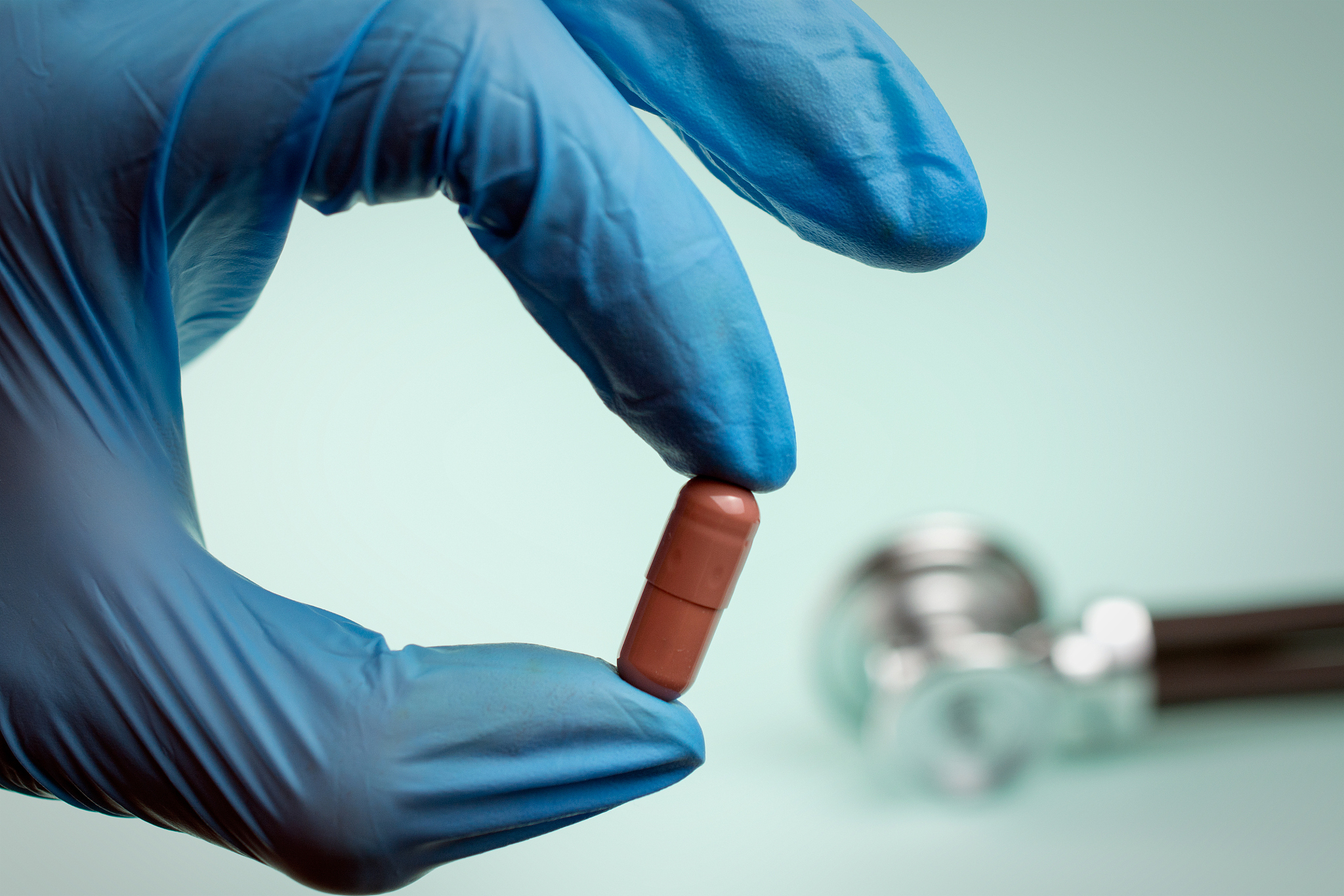 pill with fingers in gloves. opioid epidemic,