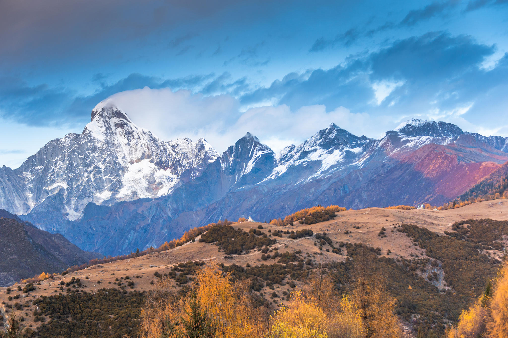 mountain peak in sunset with landscape of forest and snow capped