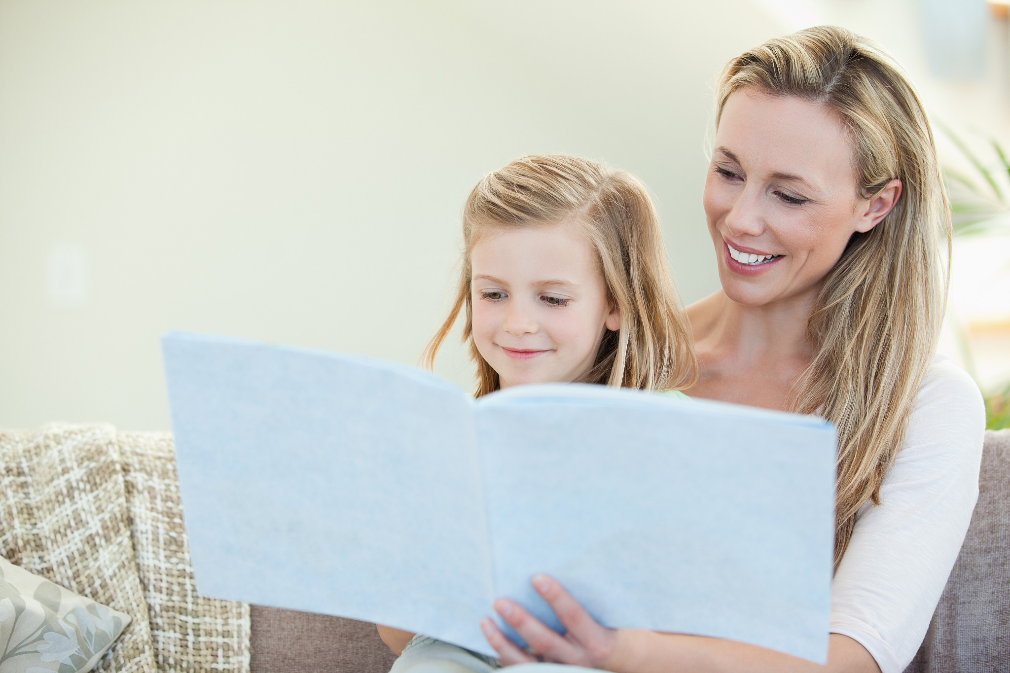 mother and daughter reading together on the couch