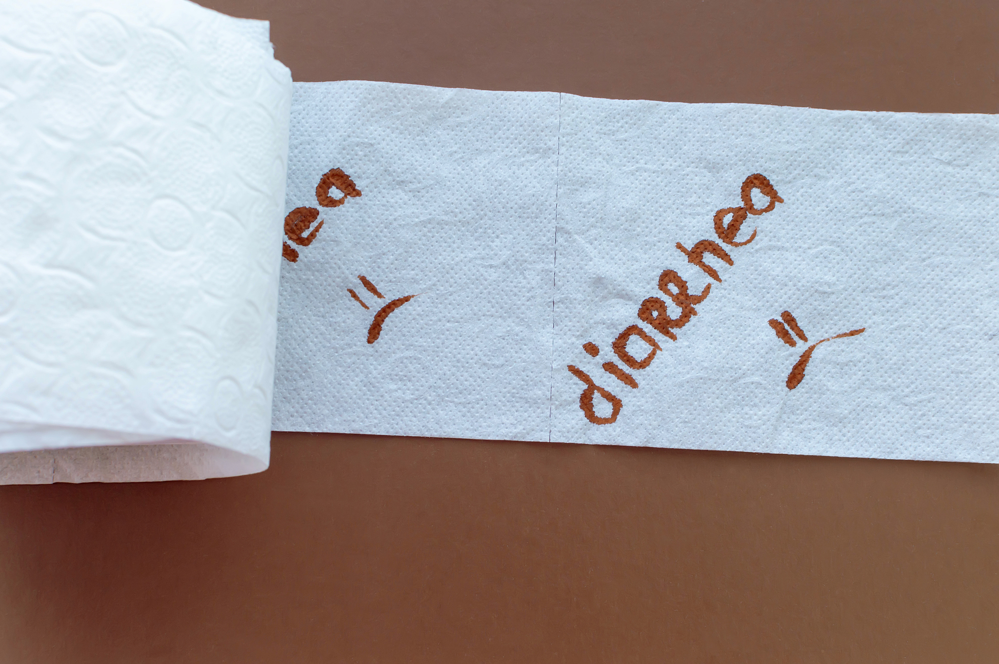 a roll of white toilet paper labeled "diarrhea" on a brown backg