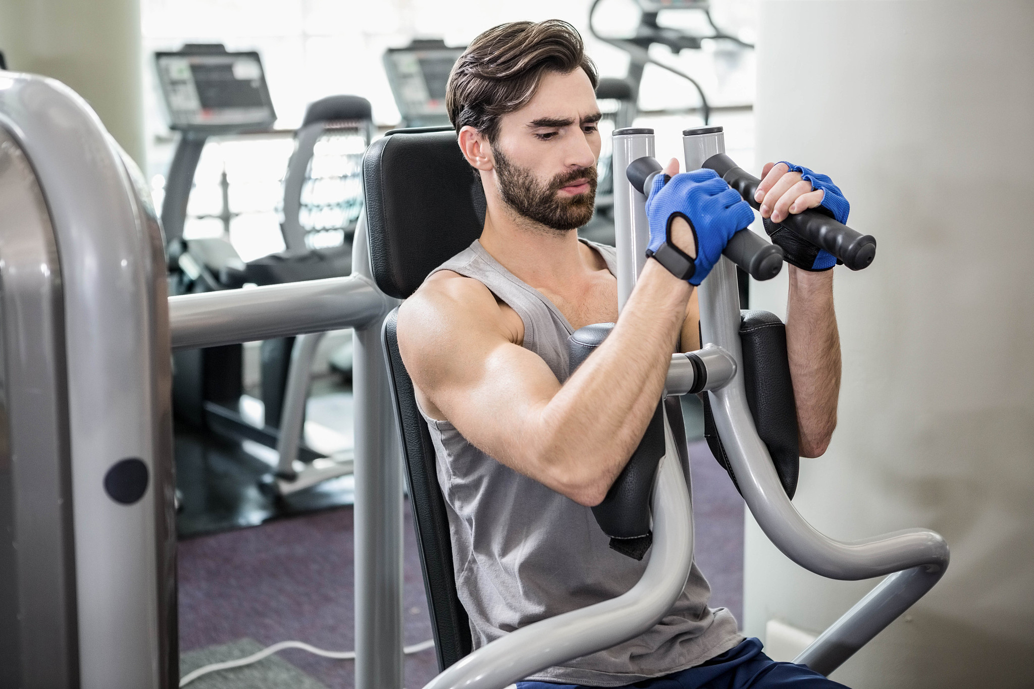 focused man using weights machine for arms