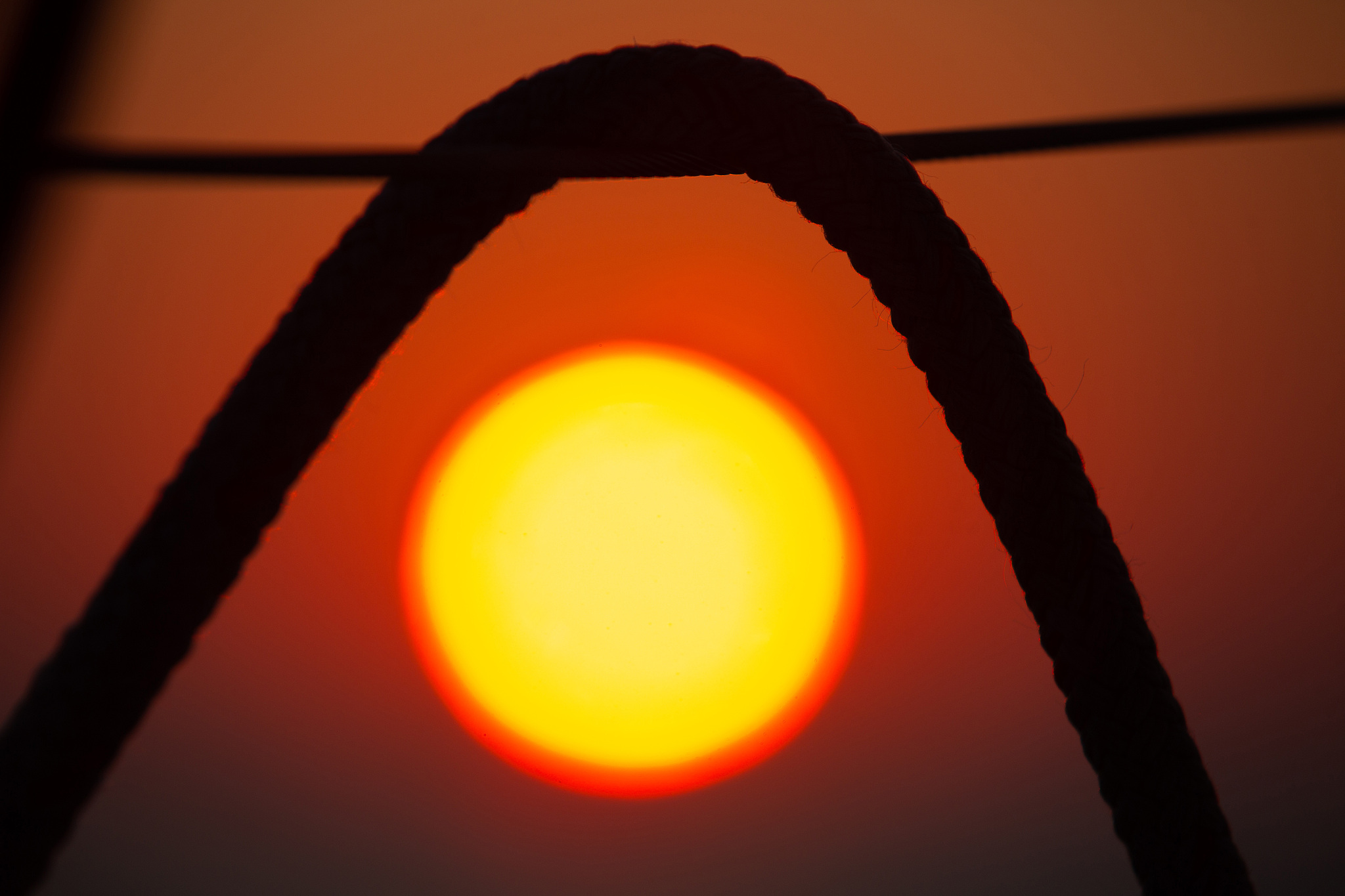 red sunset between sailing ropes
