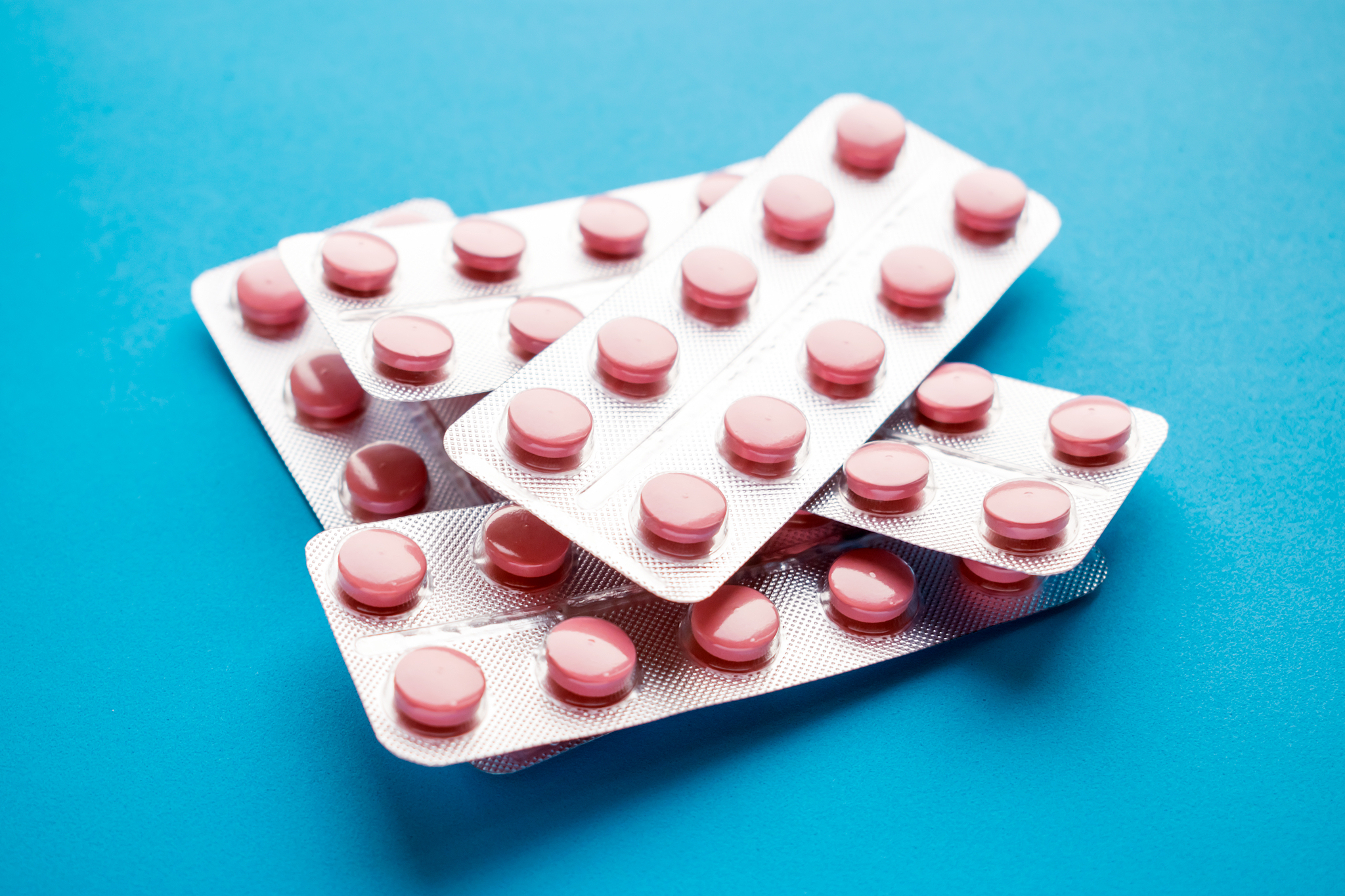 medicine pink pills or tablets in silvery blisters on blue backg
