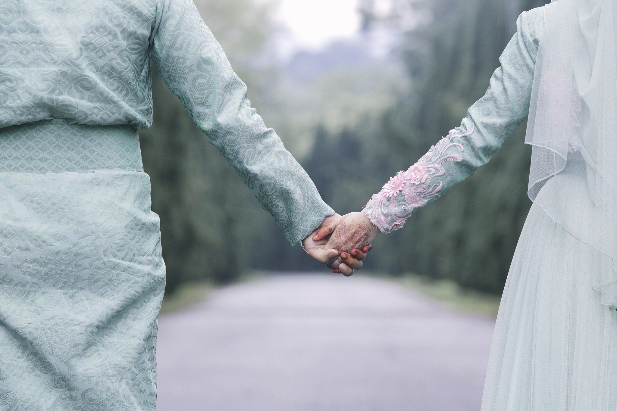 midsection of couple holding hands against tree