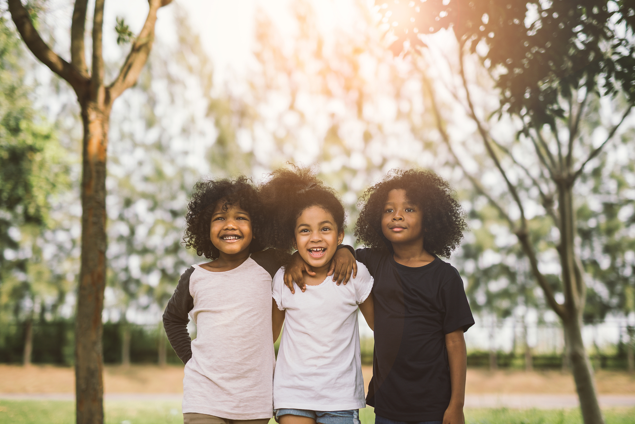 happy friends standing against trees in park