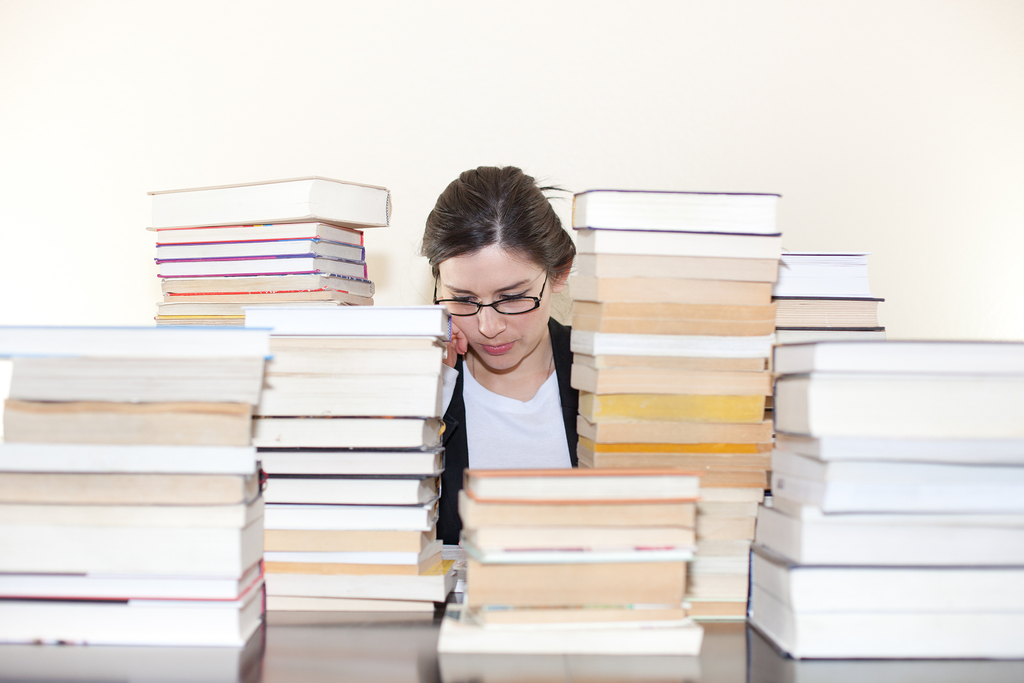 woman sitting at table, surrounded by books