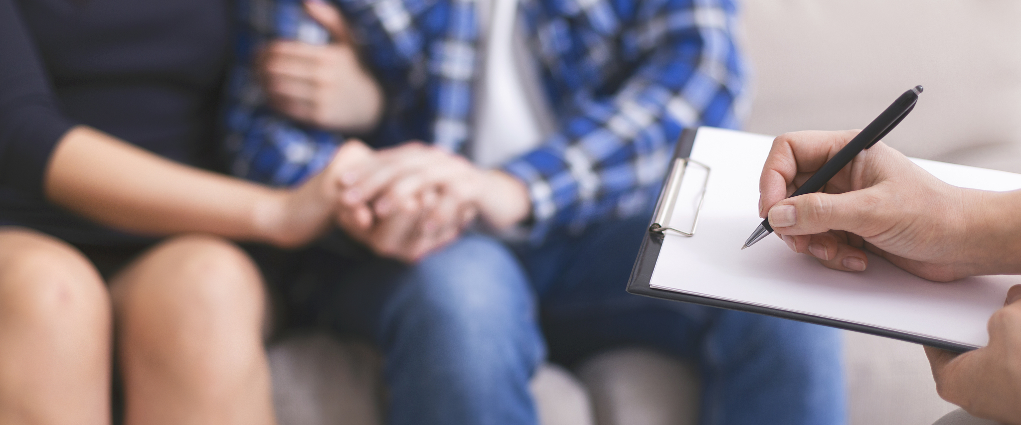 worried couple holding hands, specialist writing report in notep