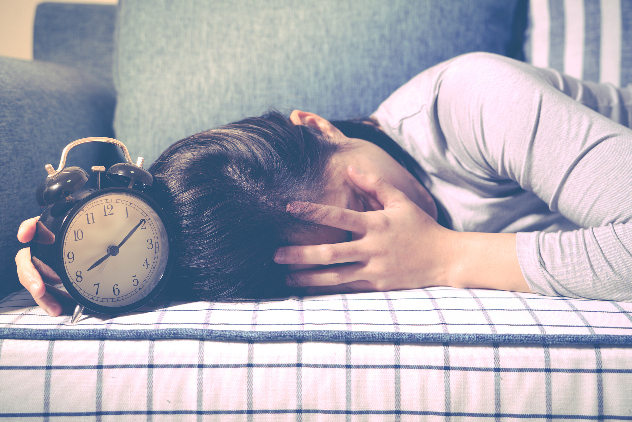 lazy women is laying down on the sofa after the clock alarm, lat