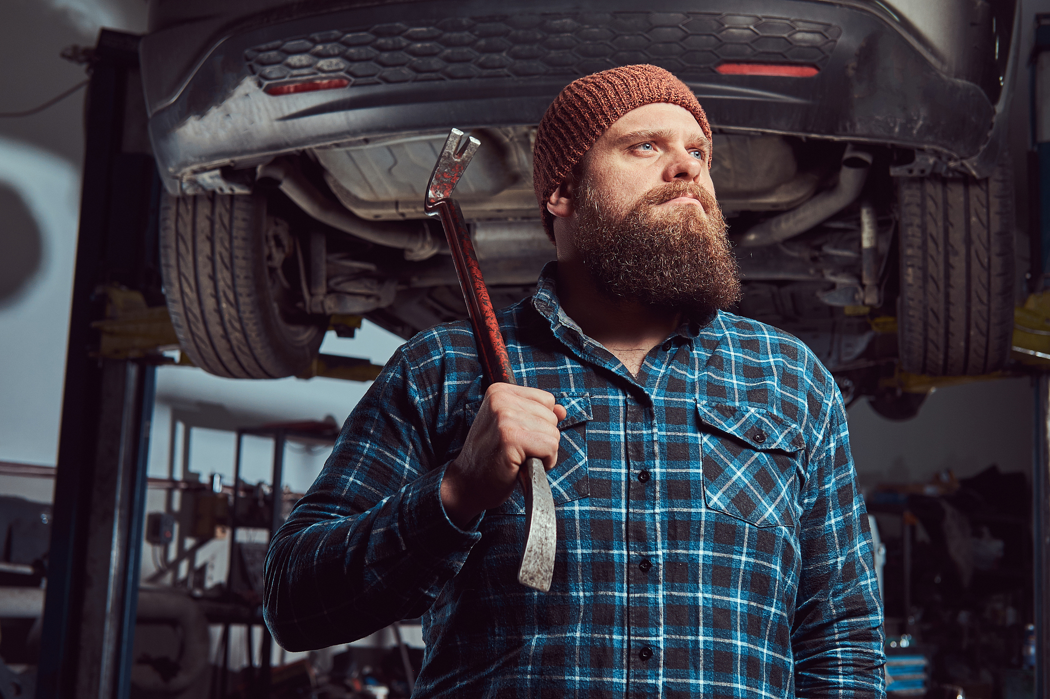 two bearded brutal mechanics repair a car on a lift in the garag