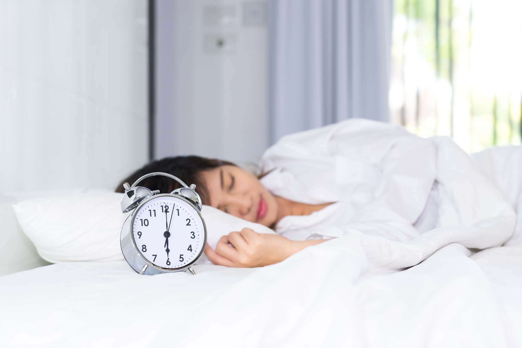 sleep woman in the morning with alarm clock.