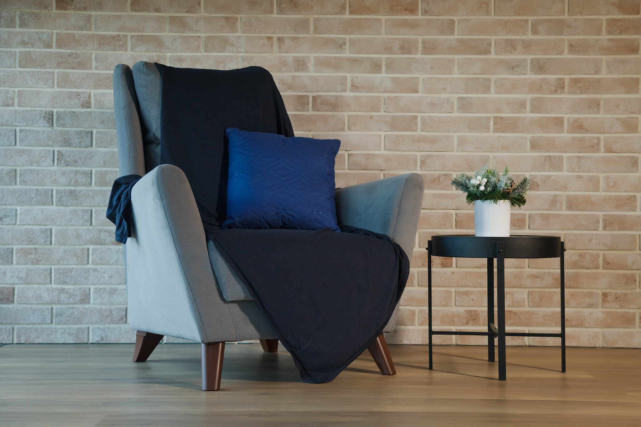 grey armchair with table in living room interior at brick wall
