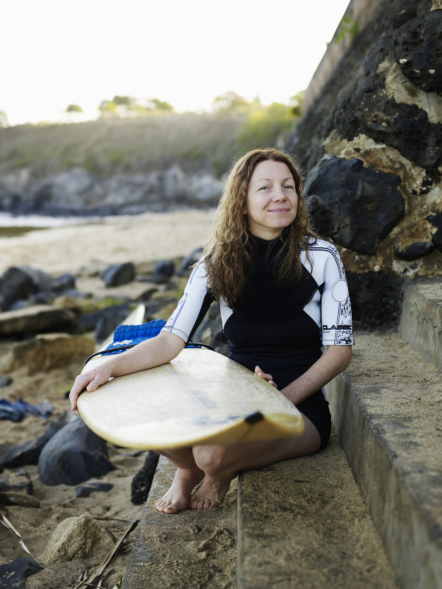 female surfer holding board on beach