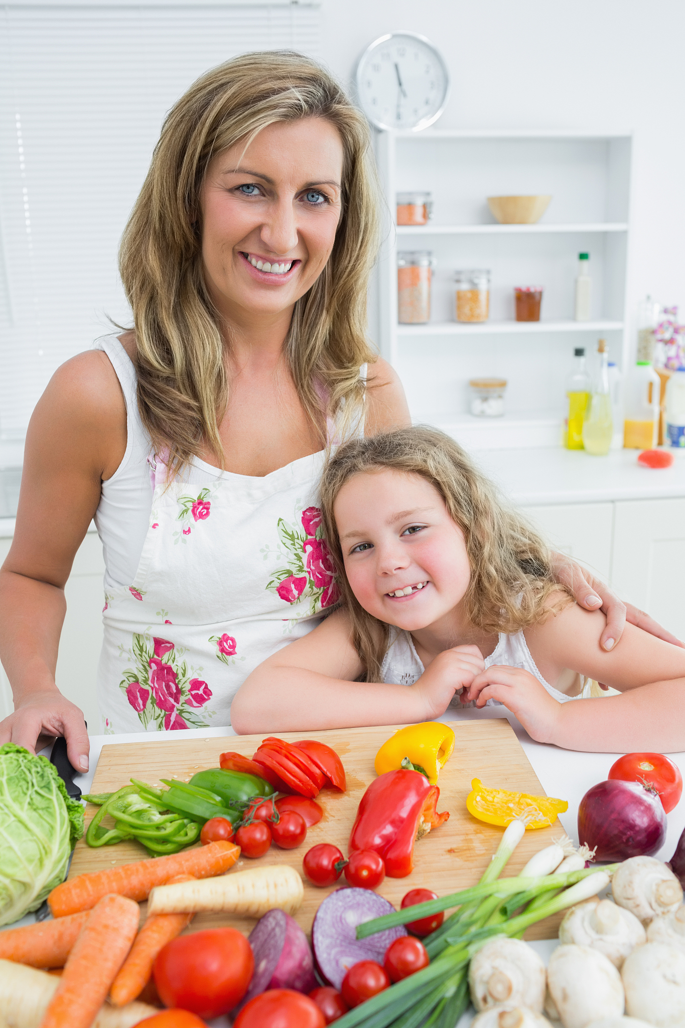 smiling mother and daughter standing at the table full of vegeta