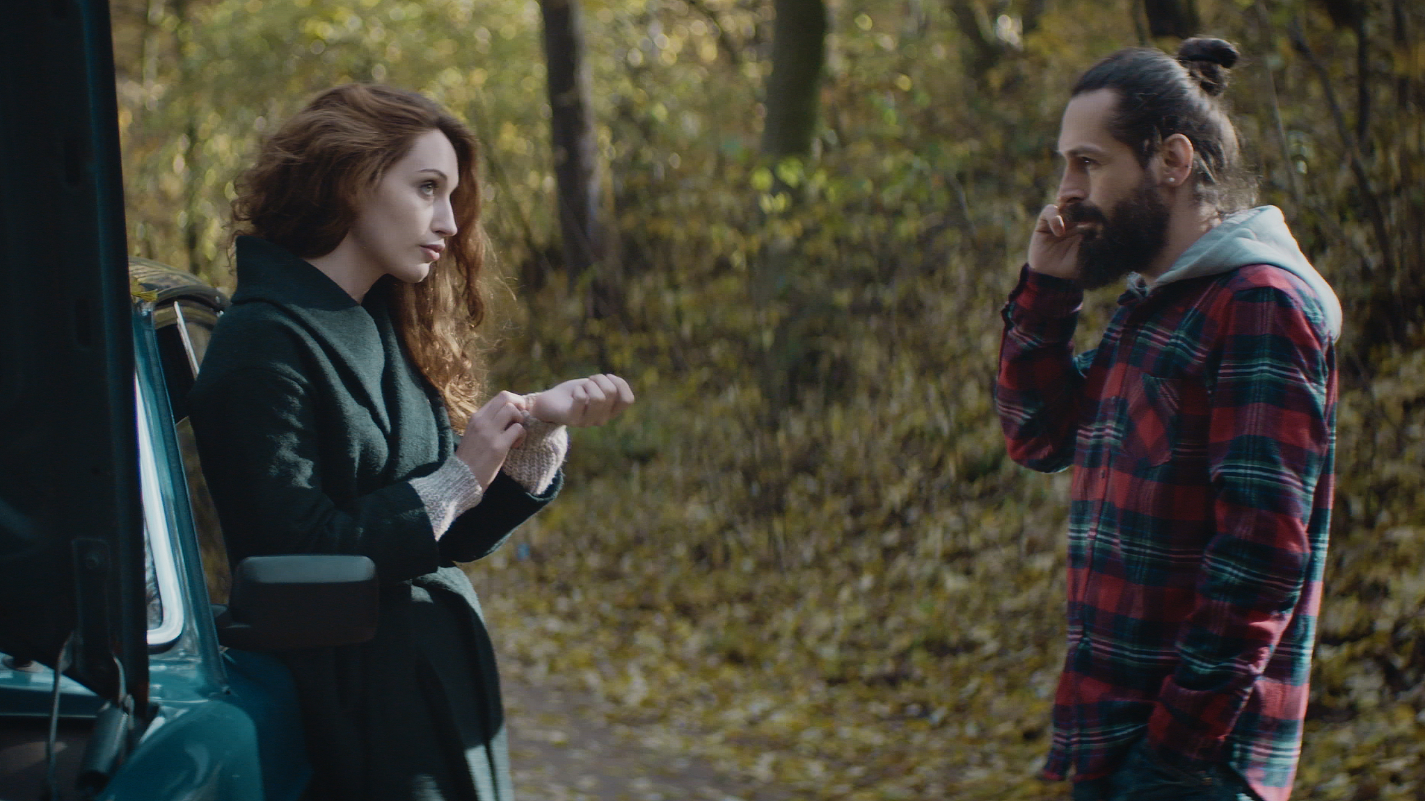 young couple with broken car in forest