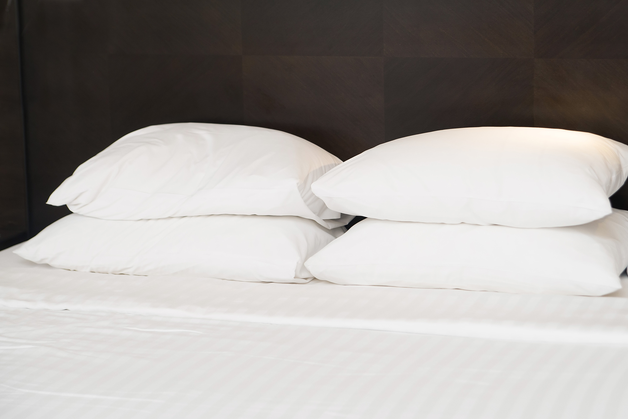 four white pillows on the bed in hotel