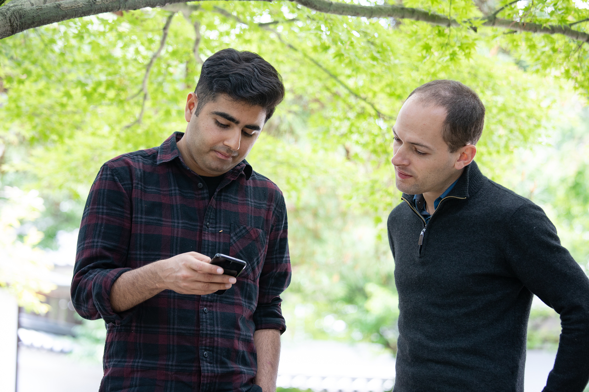 two male friends using smart phone at temple