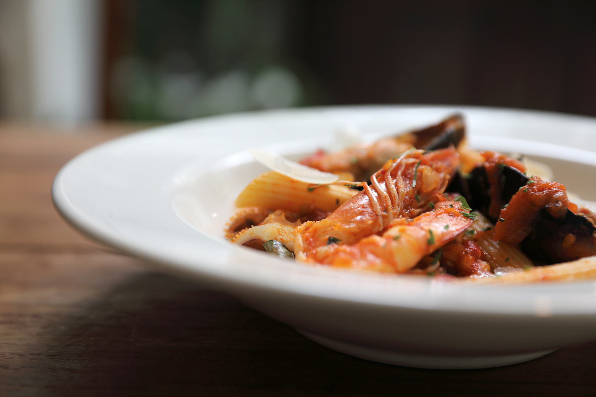 penne pasta tomato sauce arabiata with seafood on wood backgroun